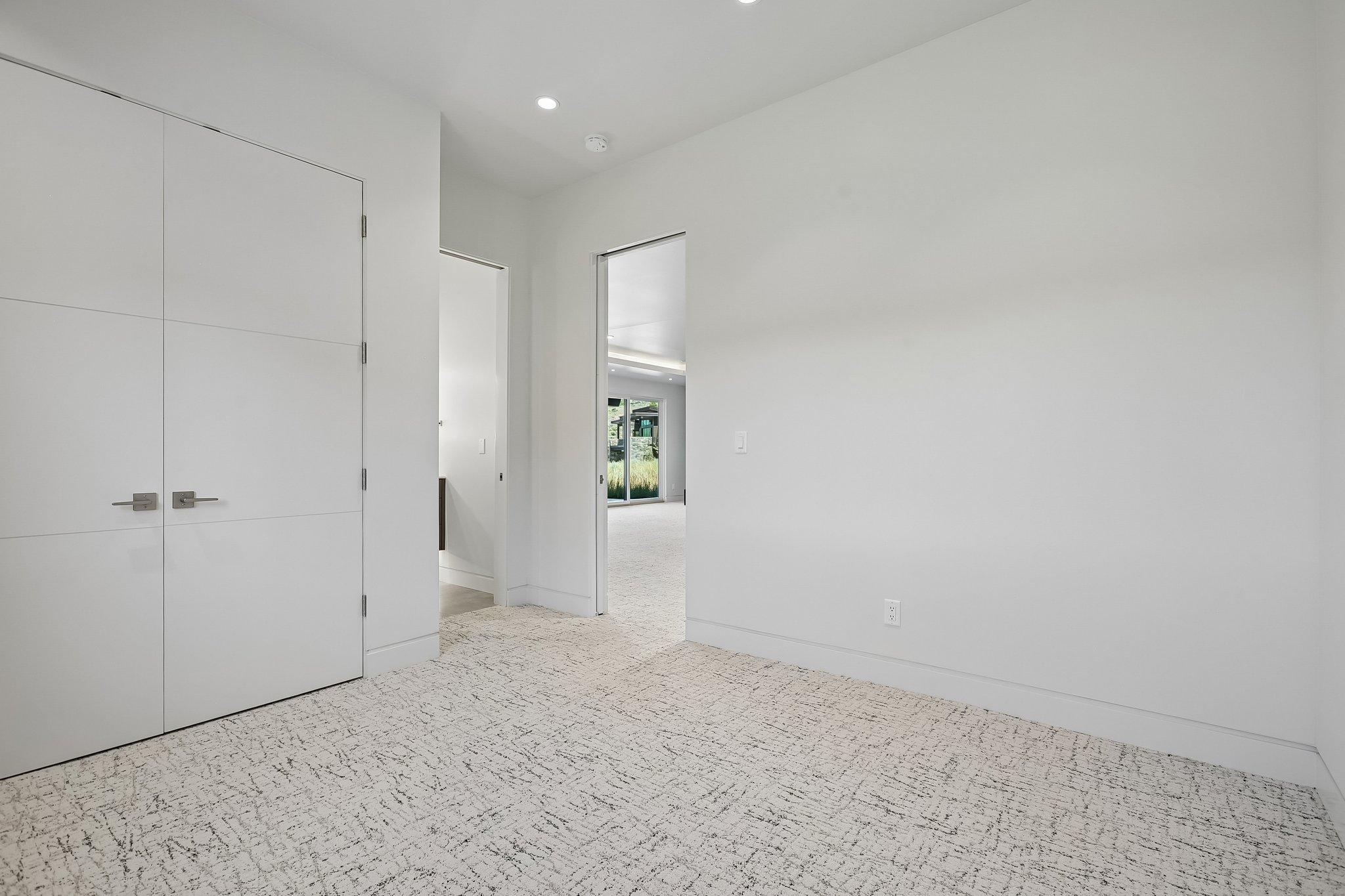 Neutral palette interior with textured carpet flooring, recessed lighting, and crisp white walls