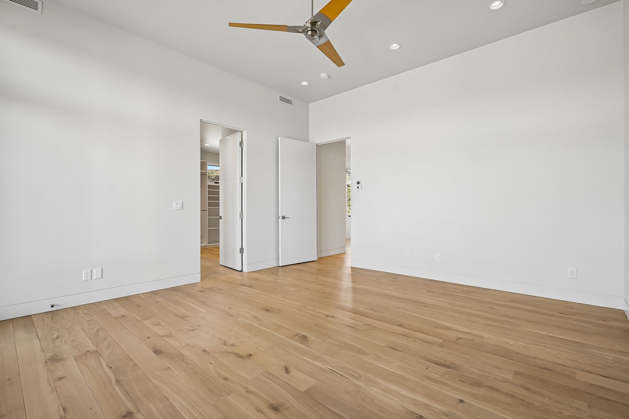 Spacious room with wood-finish flooring, recessed lighting, and a contemporary ceiling fan