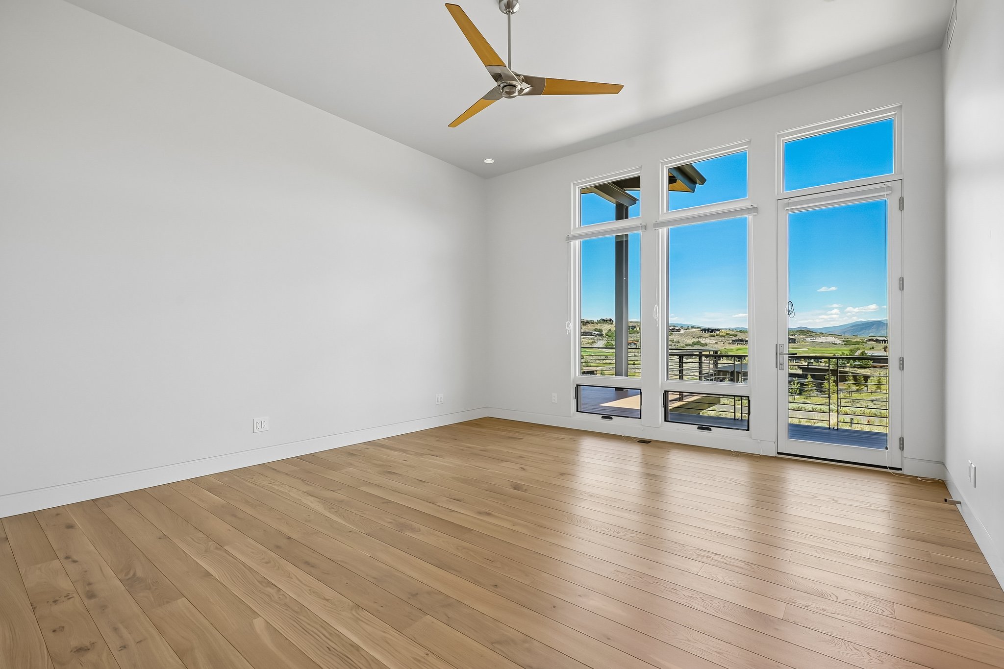 Expansive room featuring light wood-finish flooring, high ceilings, and a modern ceiling fan