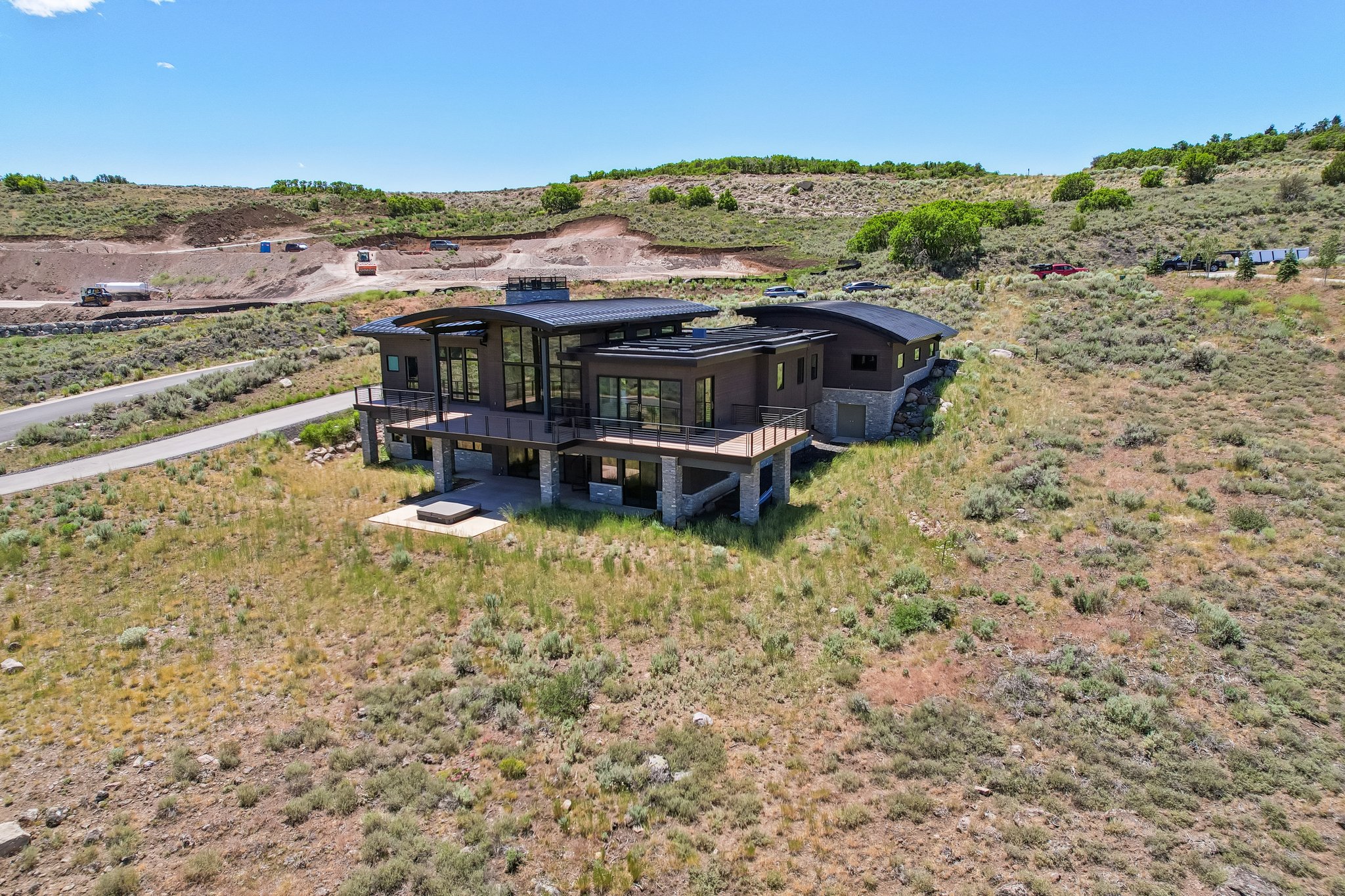 Modern architecture featuring extensive glazing, multiple outdoor decks, a lower-level patio, and a stone facade