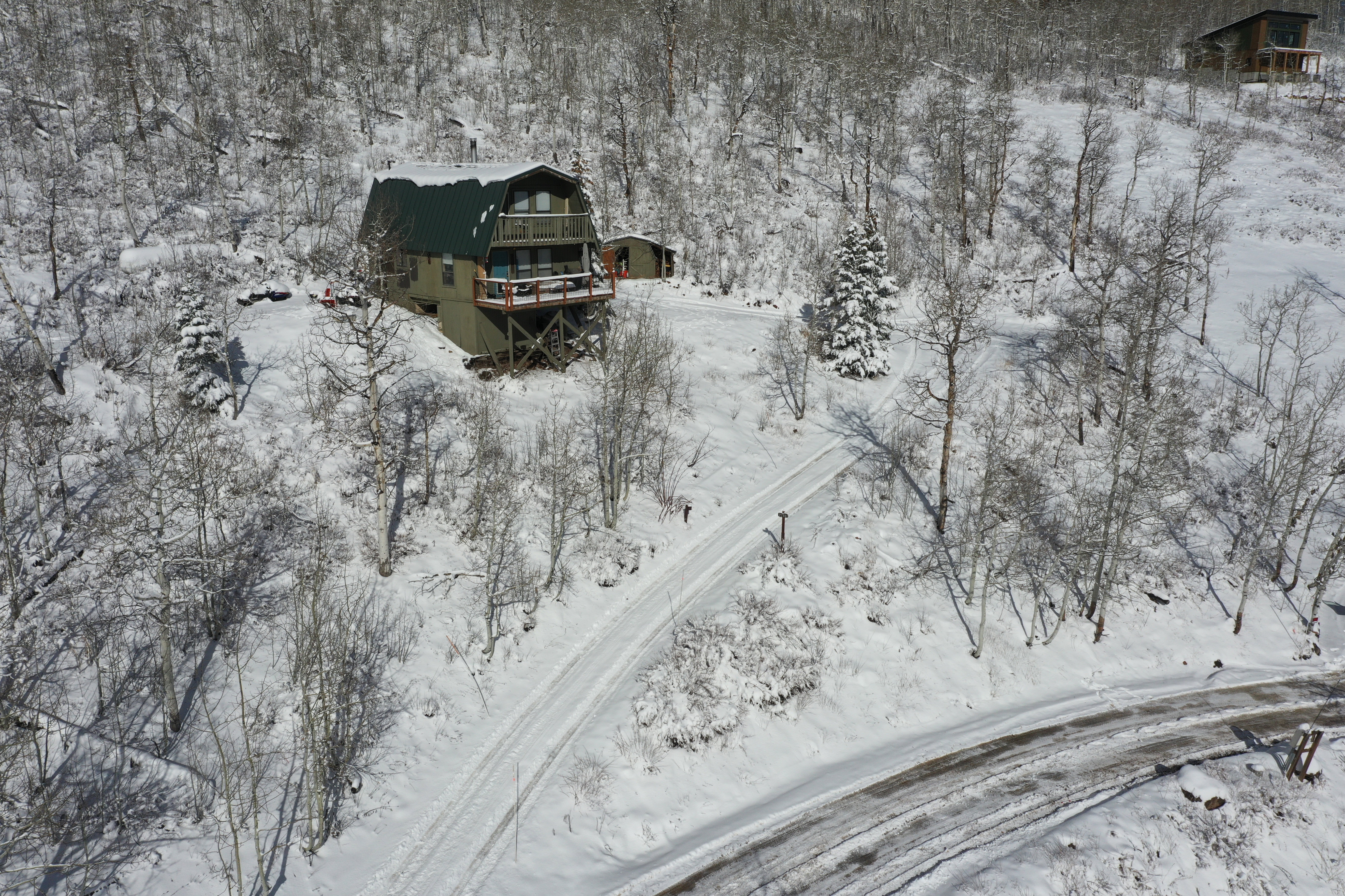 Elevated home with a green metal roof, multiple balconies, and a distinctive gambrel roofline