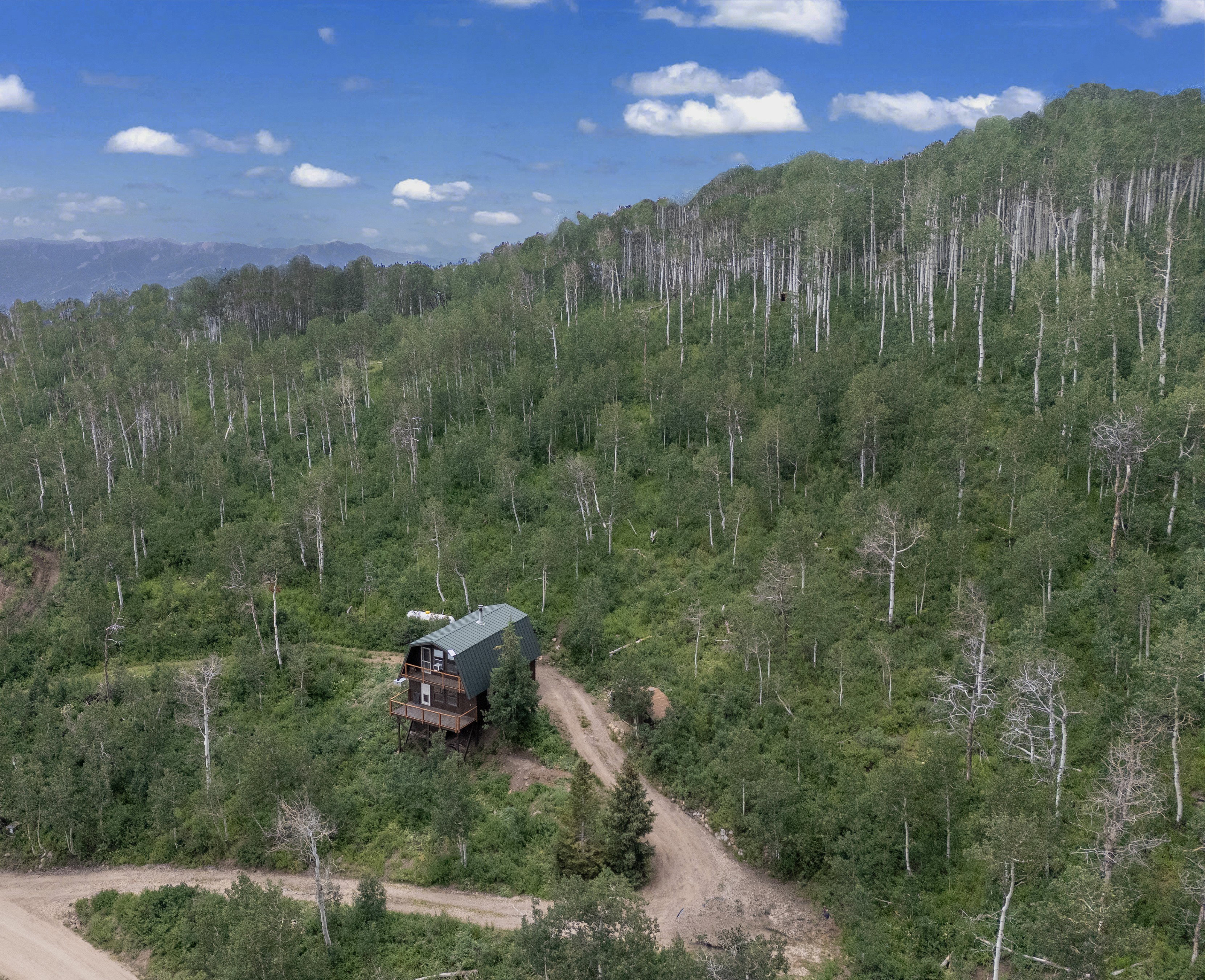 Mountain home with a green gable roof, featuring a multi-level deck and a natural wood exterior