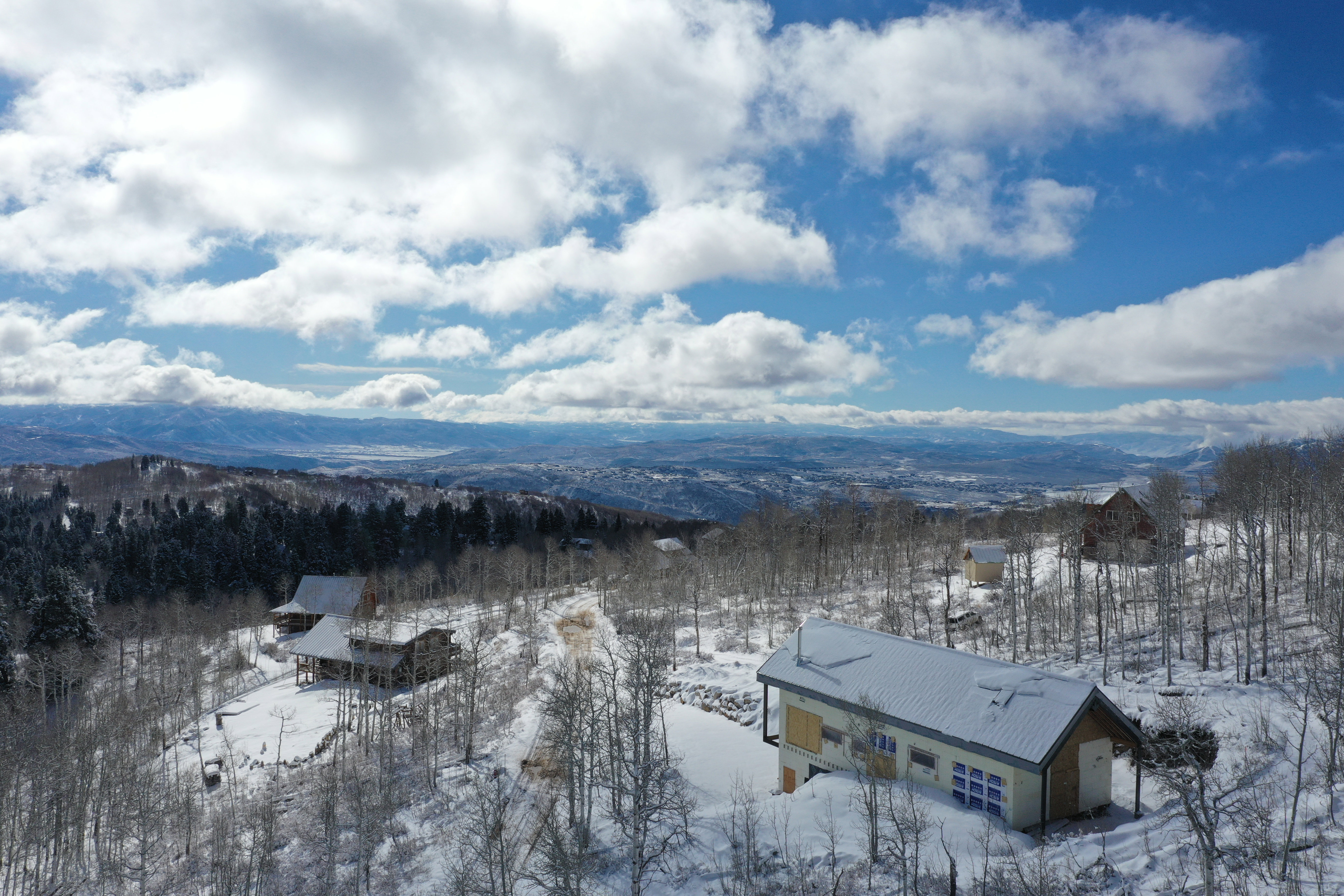 Expansive mountain landscape featuring multiple structures amidst a snowy, wooded terrain
