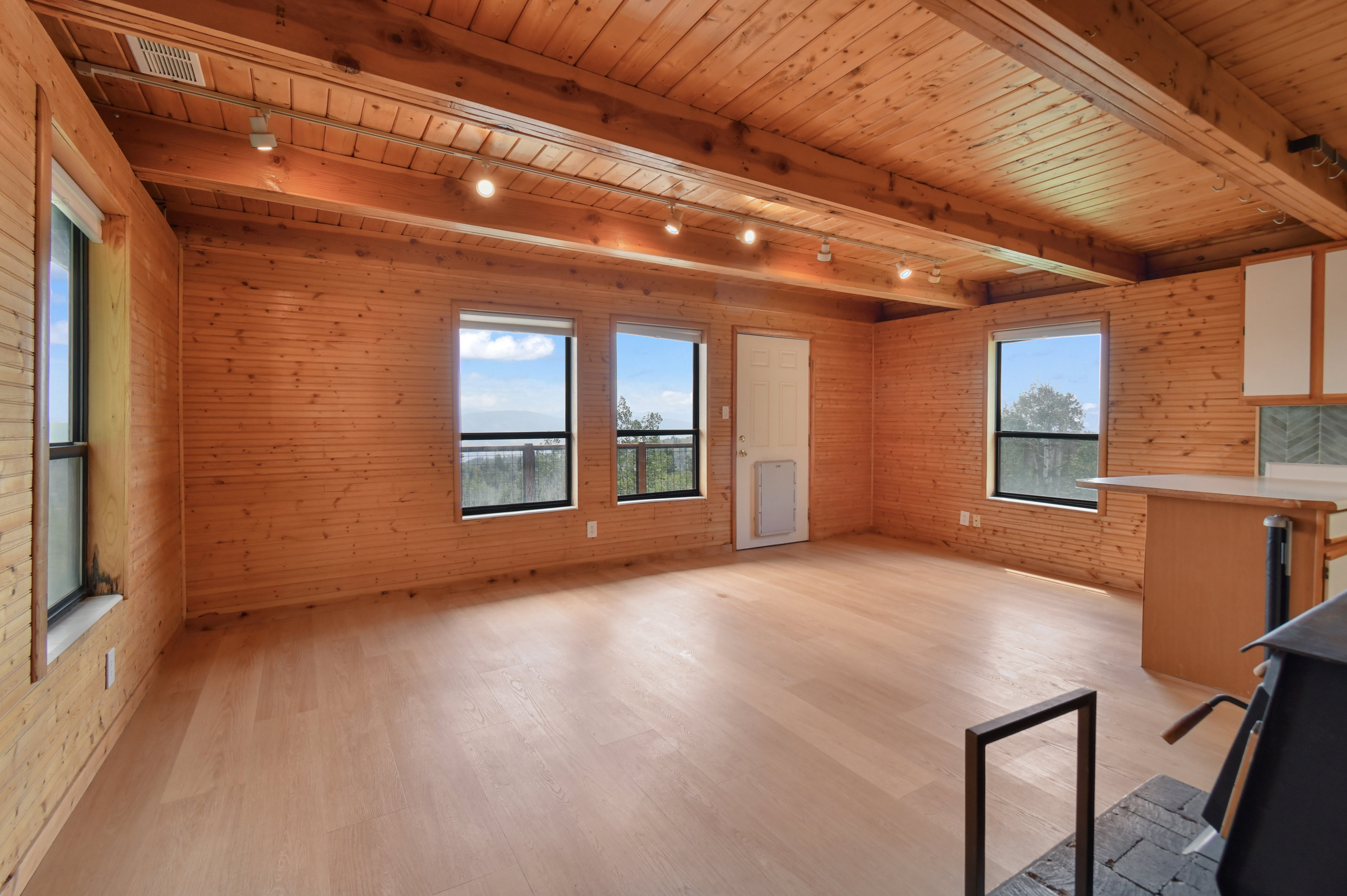 Open concept interior featuring natural wood paneling, wood-finish flooring, and exposed ceiling beams