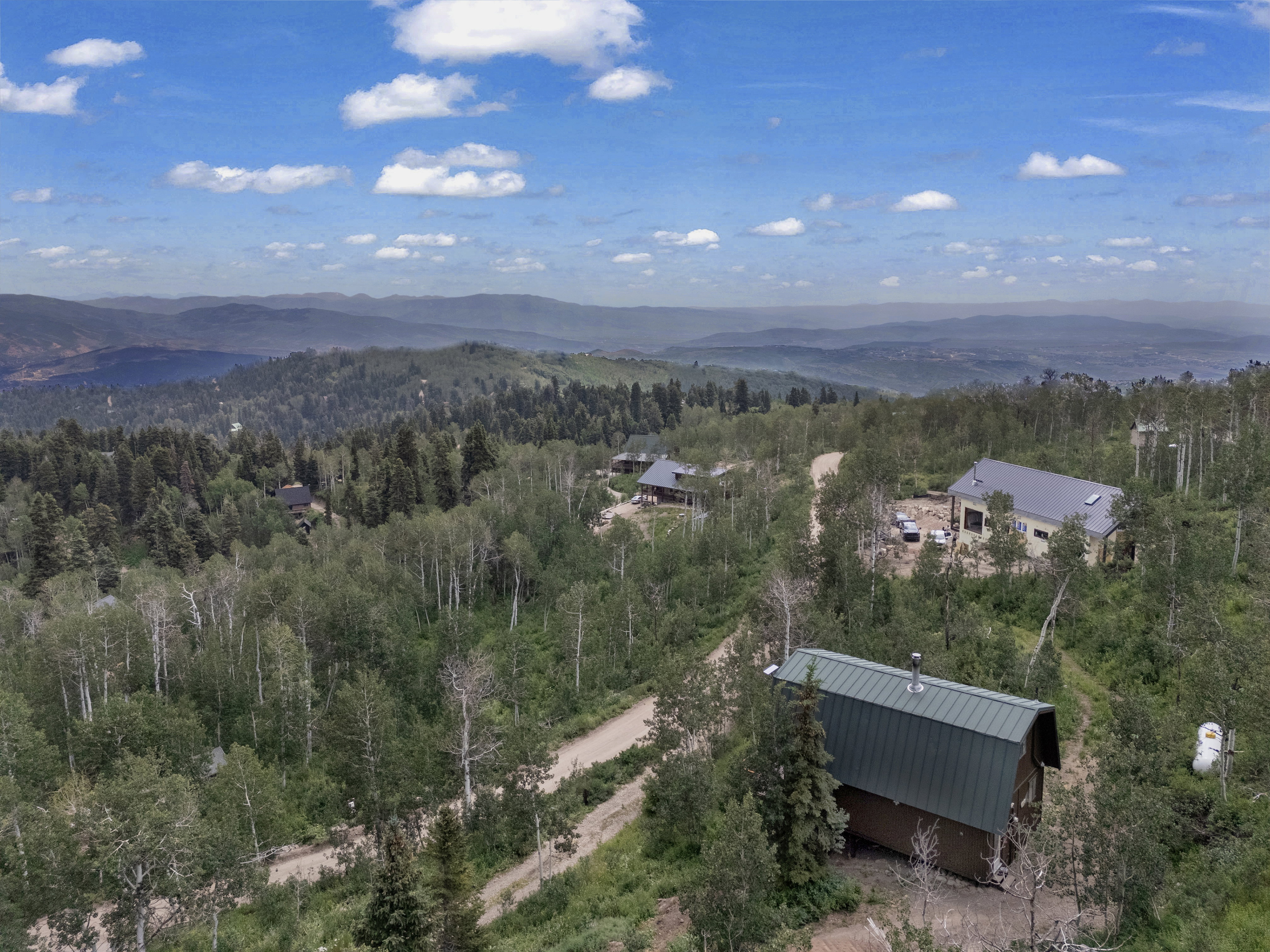 Expansive mountain setting with multiple structures surrounded by dense tree coverage