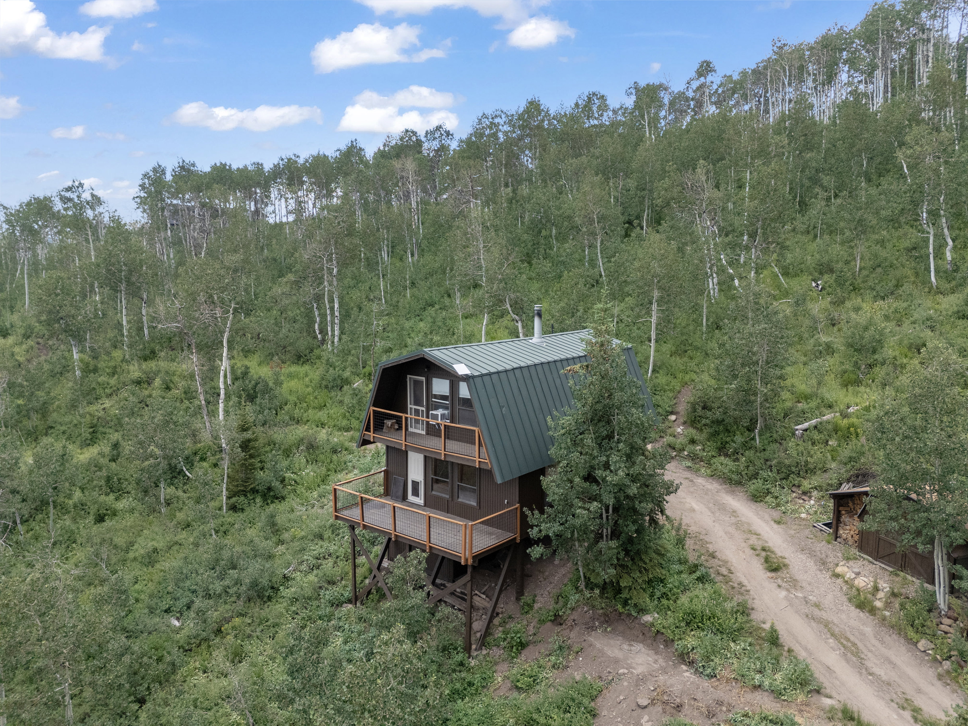 Rustic cabin structure featuring a dark brown exterior and a green metal gambrel roof