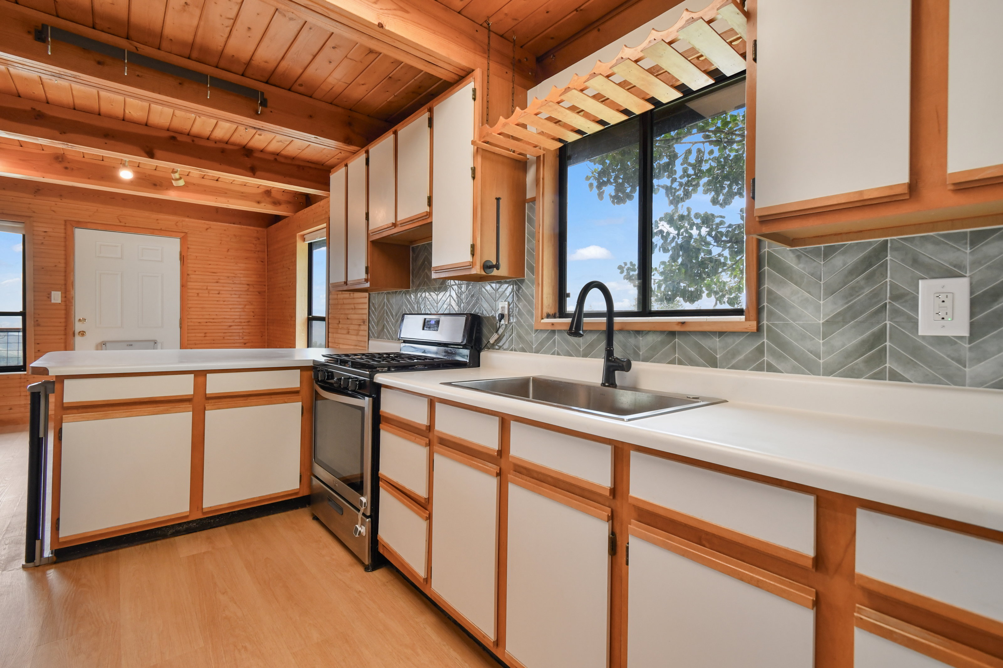 Kitchen featuring wood-finish flooring, wood-paneled walls, and exposed wood ceiling beams