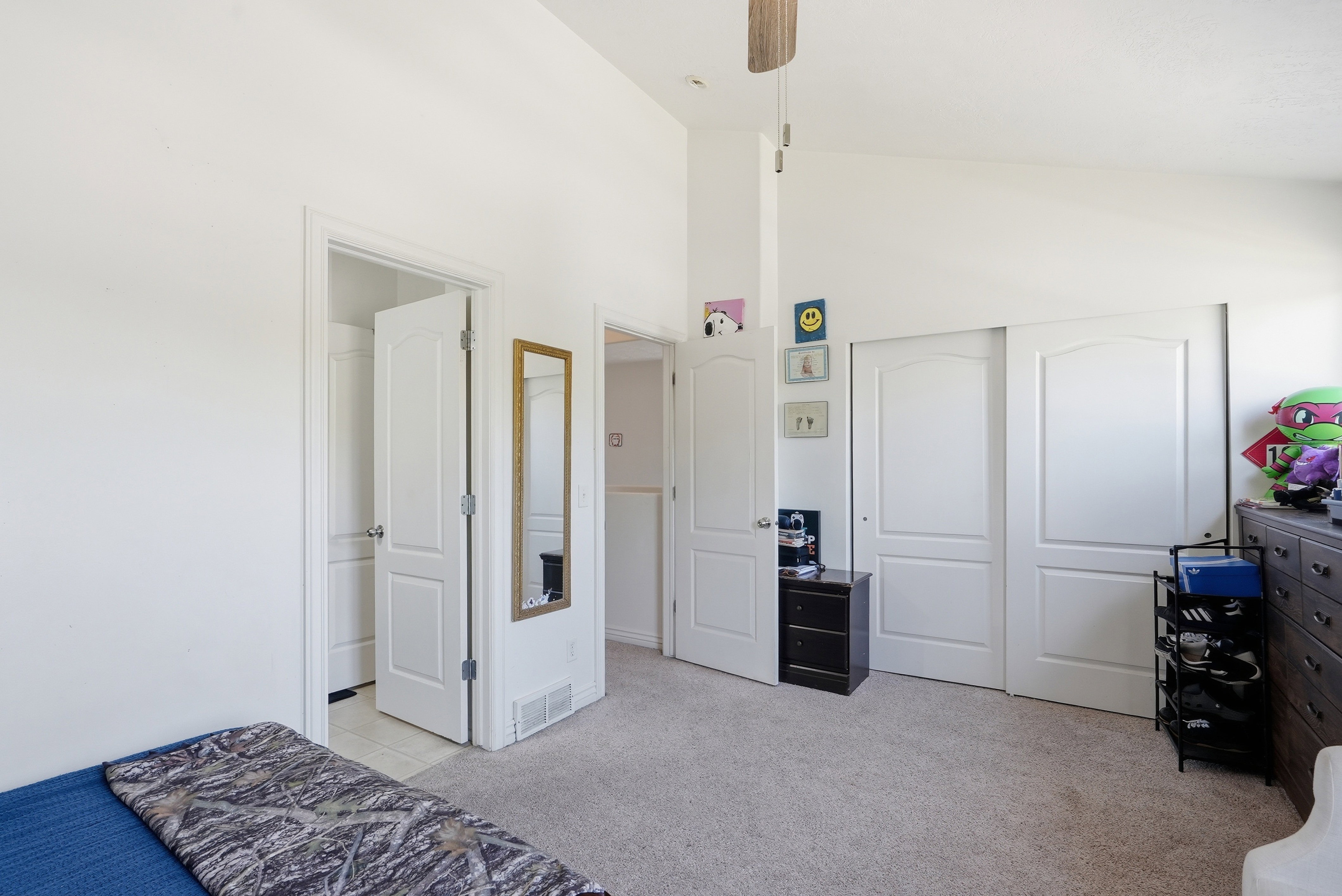 Spacious interior featuring a vaulted ceiling, wood-finish ceiling fan, and light-toned carpeting