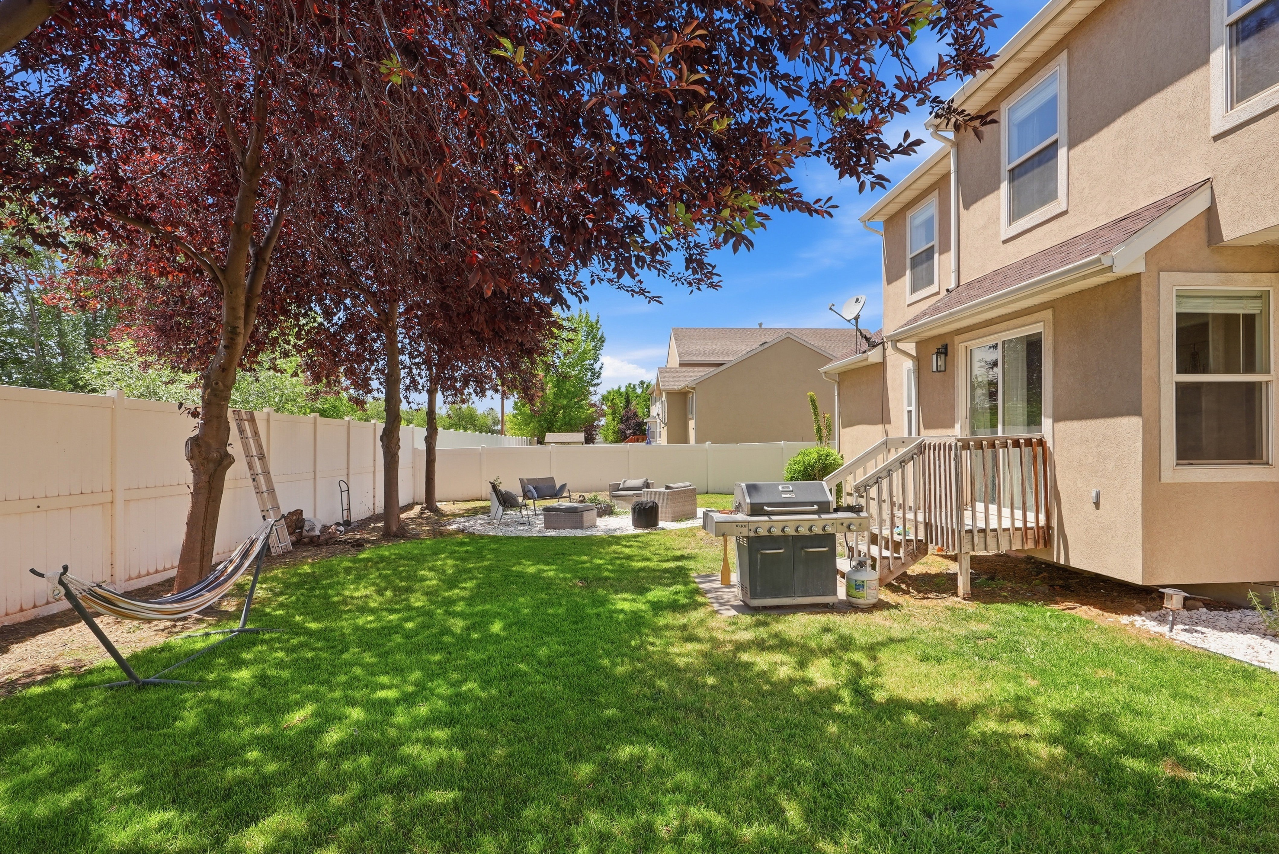 Expansive backyard featuring a green lawn and mature trees with deep red foliage