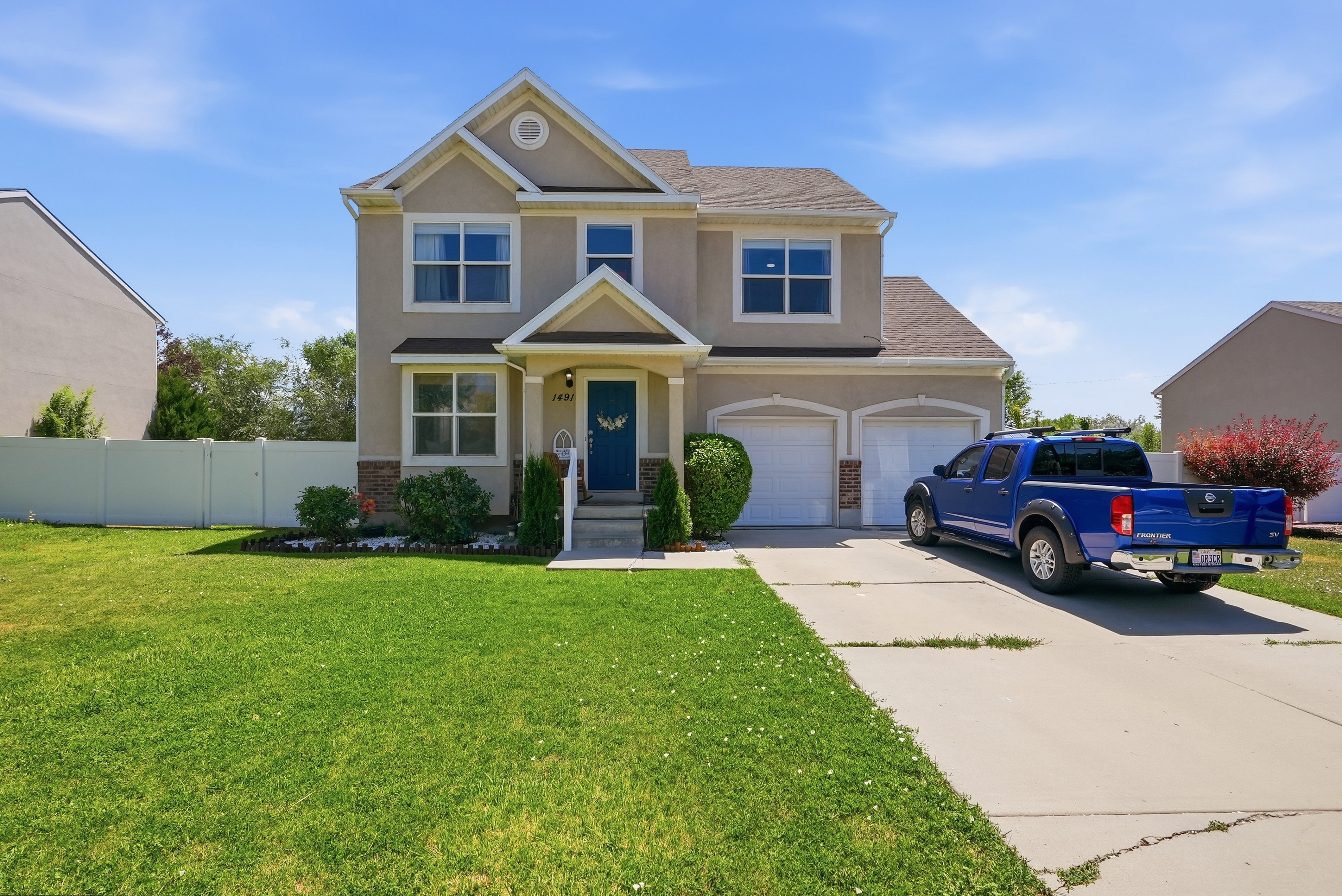 Two-story stucco residence with a prominent front entrance, dual garage doors, and a concrete driveway