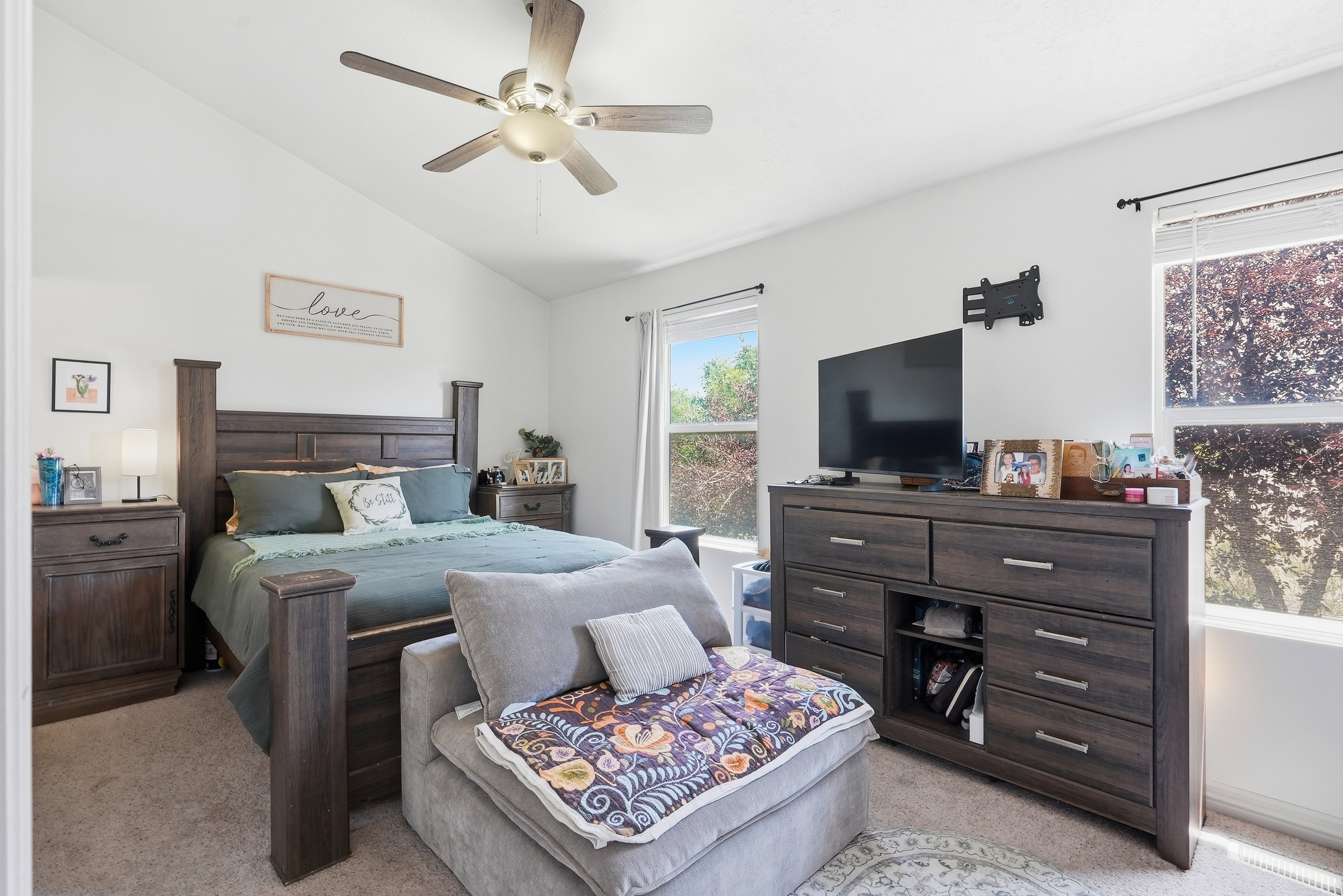 Vaulted ceilings with a ceiling fan, dual windows providing ample natural light, and neutral wall paint