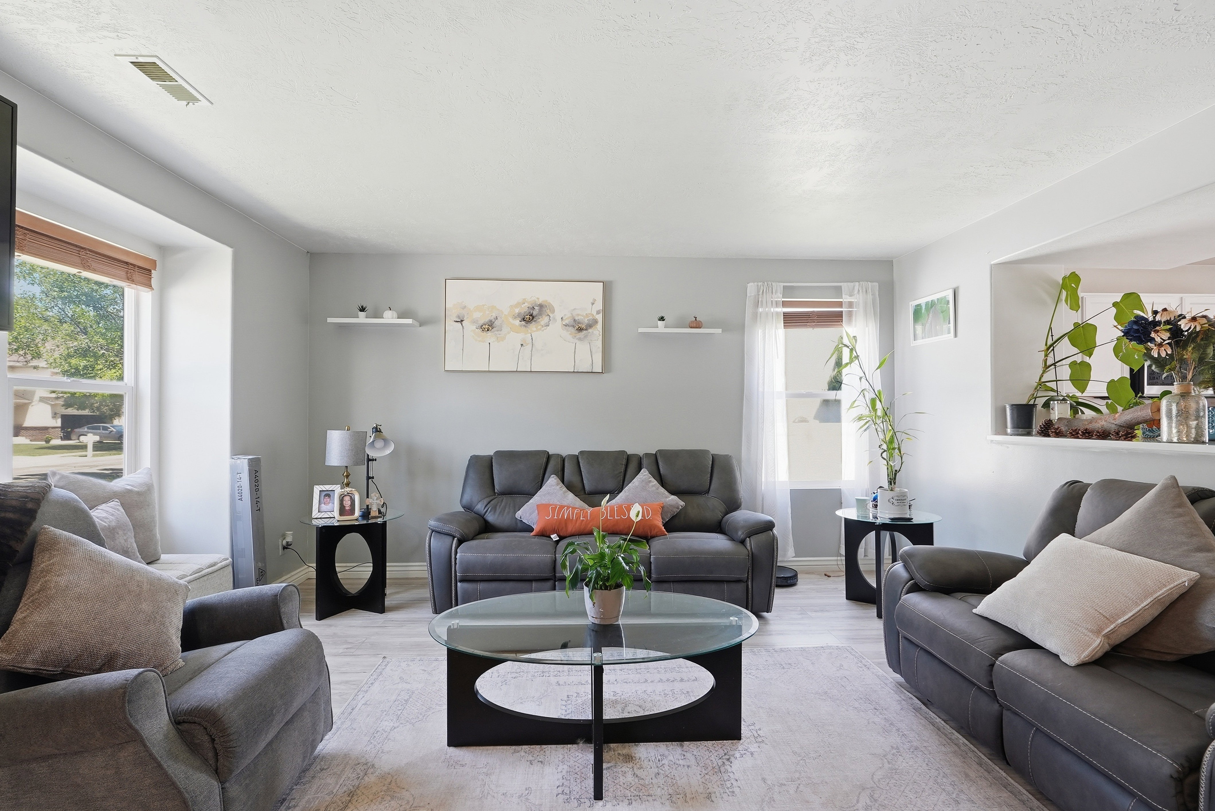 Living area featuring light gray walls, wood-finish flooring, and multiple windows