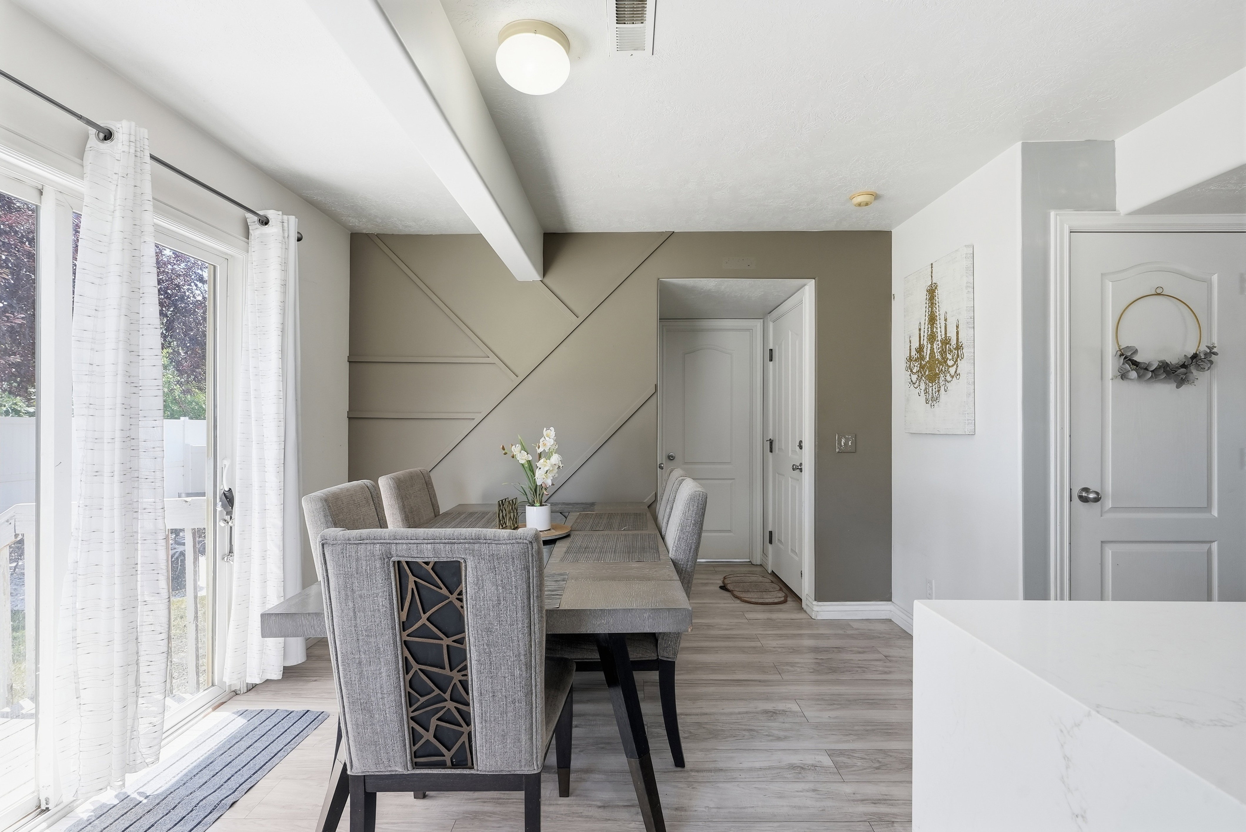 Dining area featuring light wood-finish flooring, a textured accent wall, and a ceiling beam detail