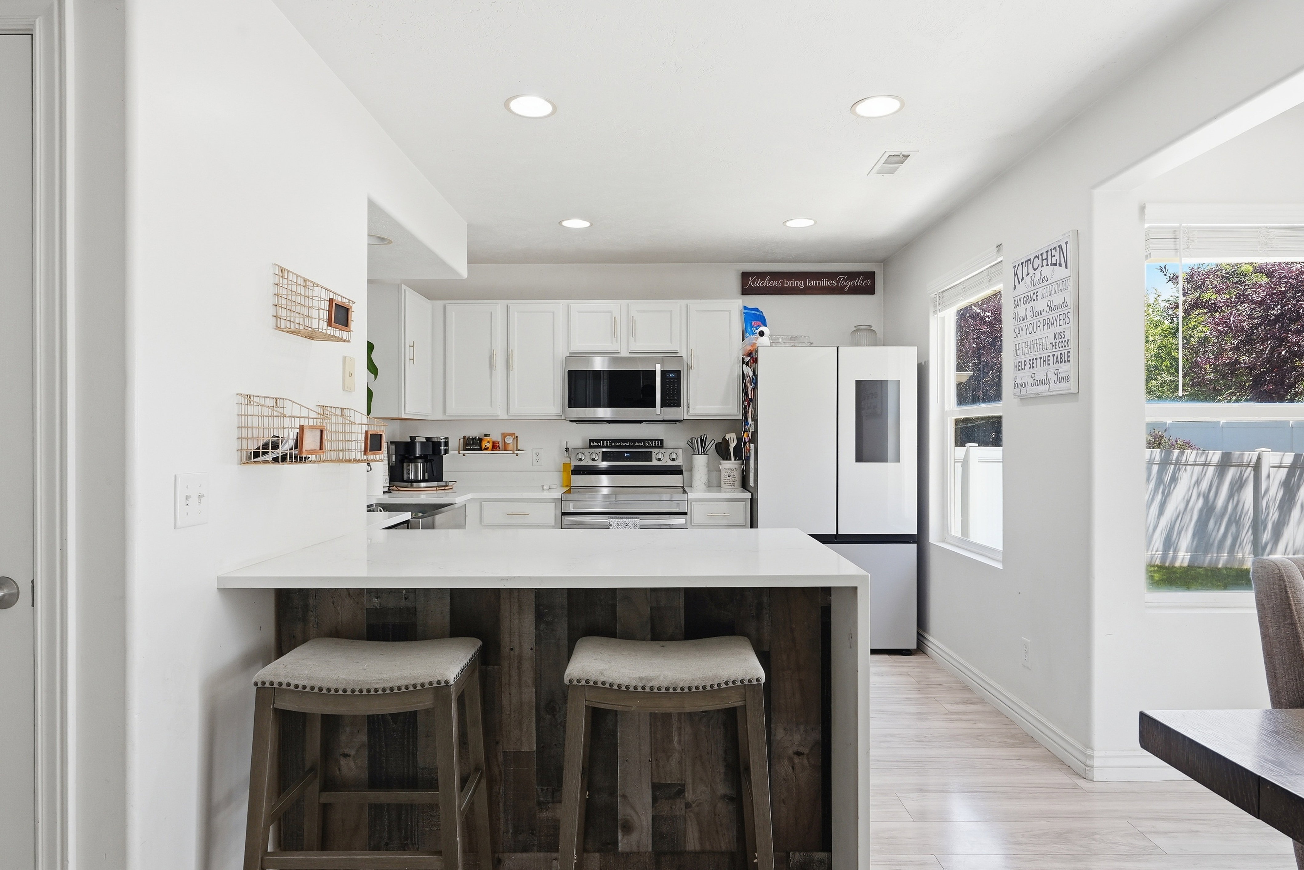 Bright kitchen featuring white cabinetry, stainless steel appliances, recessed lighting, and a wood-finish flooring