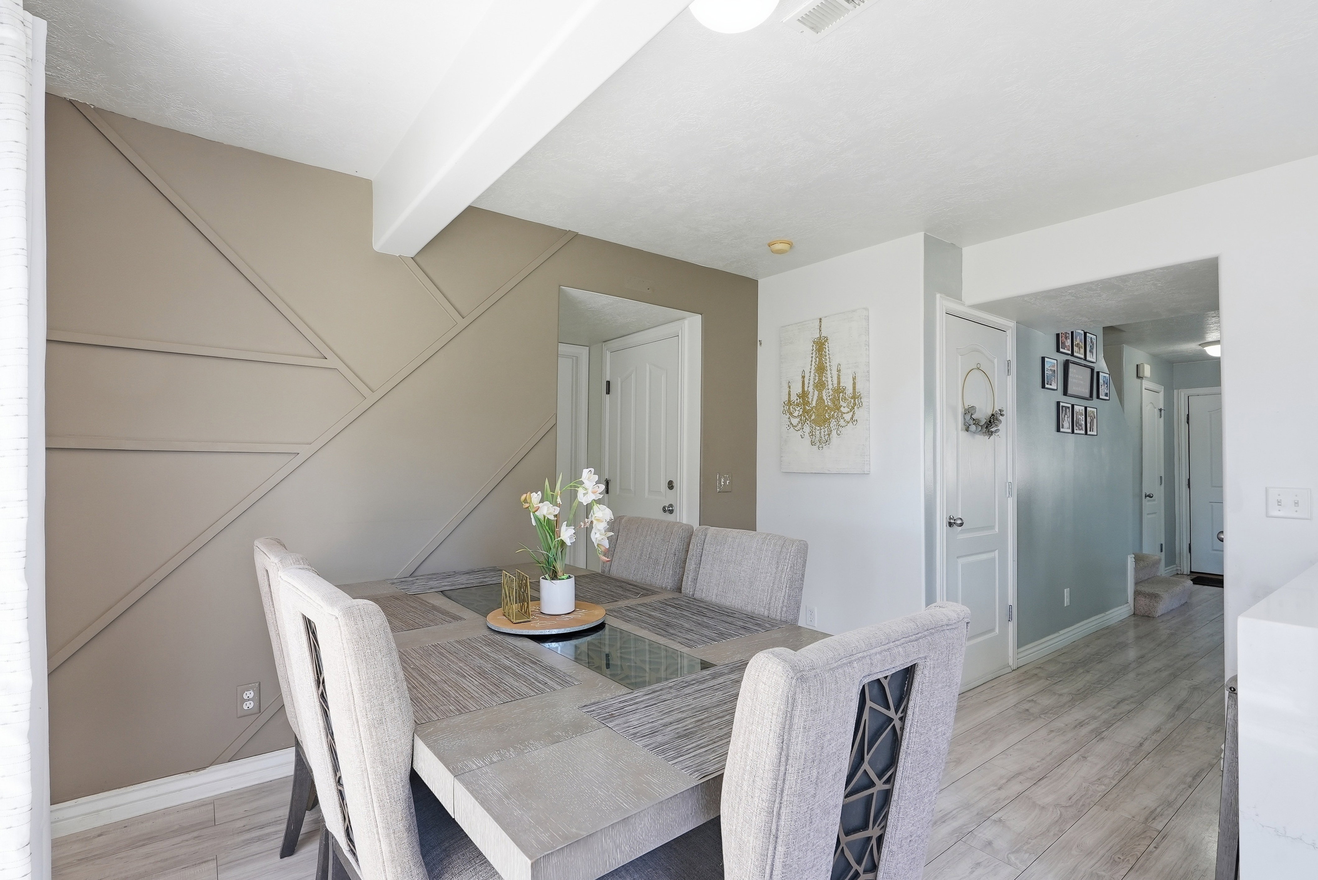 Dining area featuring an accent wall with geometric molding, light-toned wood-finish flooring, and white trim