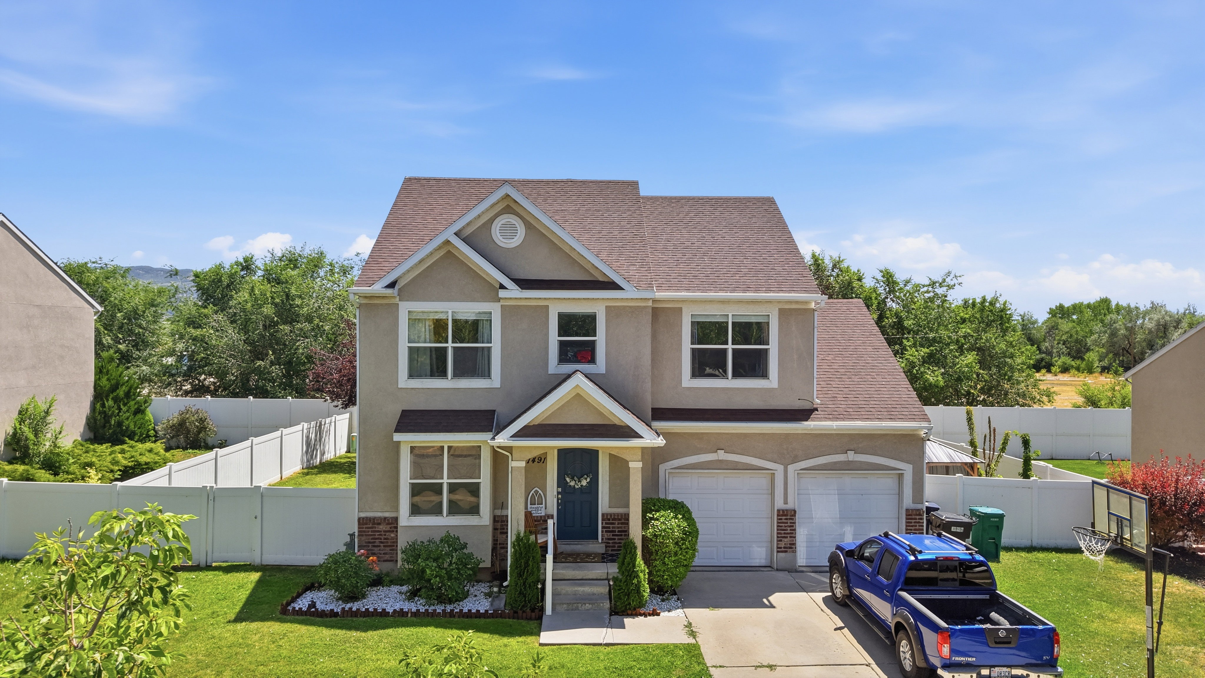 Two-story stucco home featuring a brown shingle roof and a two-car garage