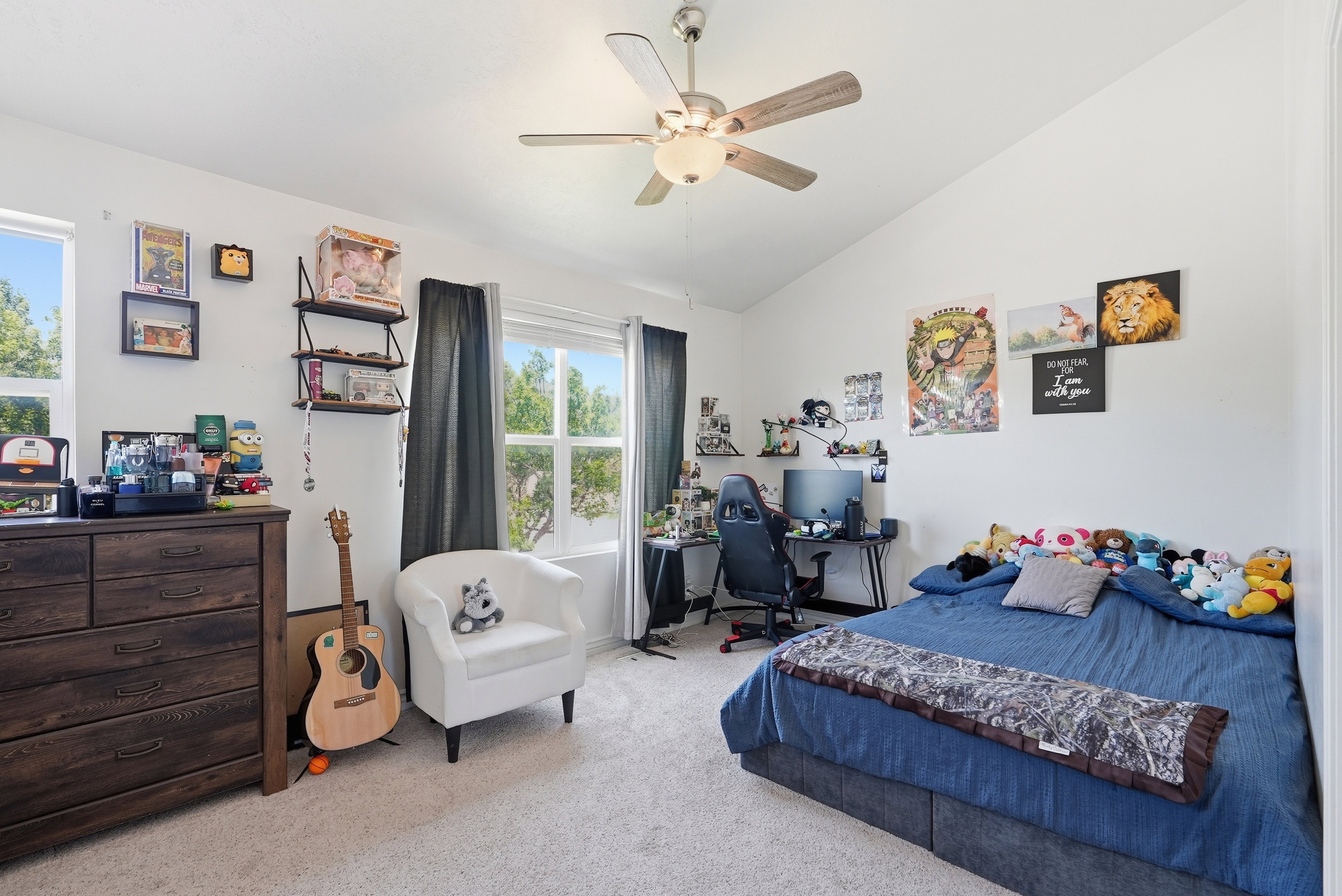 Vaulted ceiling with a ceiling fan, dual windows providing natural light, and neutral-toned carpeting throughout