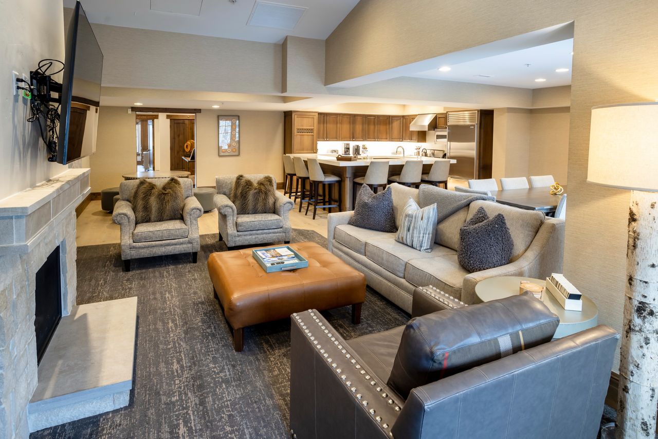 Open-concept living area featuring a stone fireplace, wood-finish flooring, recessed lighting, and a kitchen with an island and integrated appliances