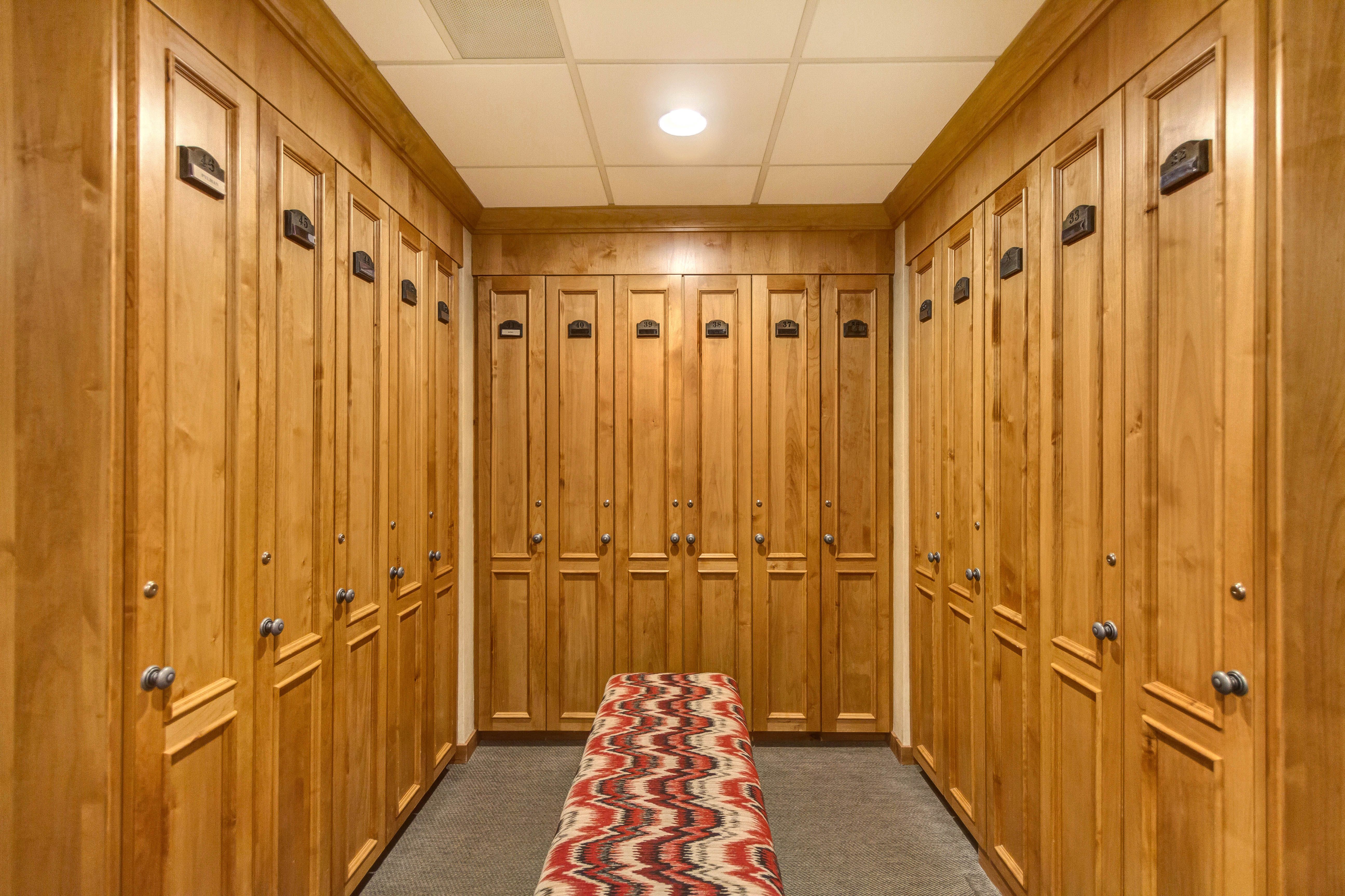 Hallway featuring abundant wood-panel lockers with brushed nickel hardware, recessed ceiling lighting, and a neutral-toned carpeted floor