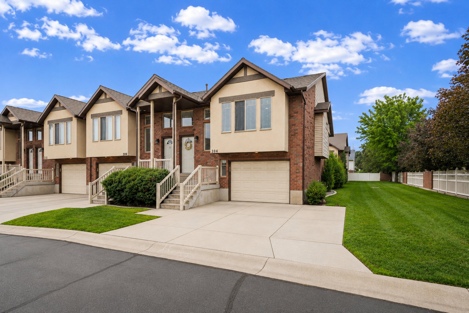 Townhome exterior featuring brick and stucco siding, a columned porch entry, and an integrated garage