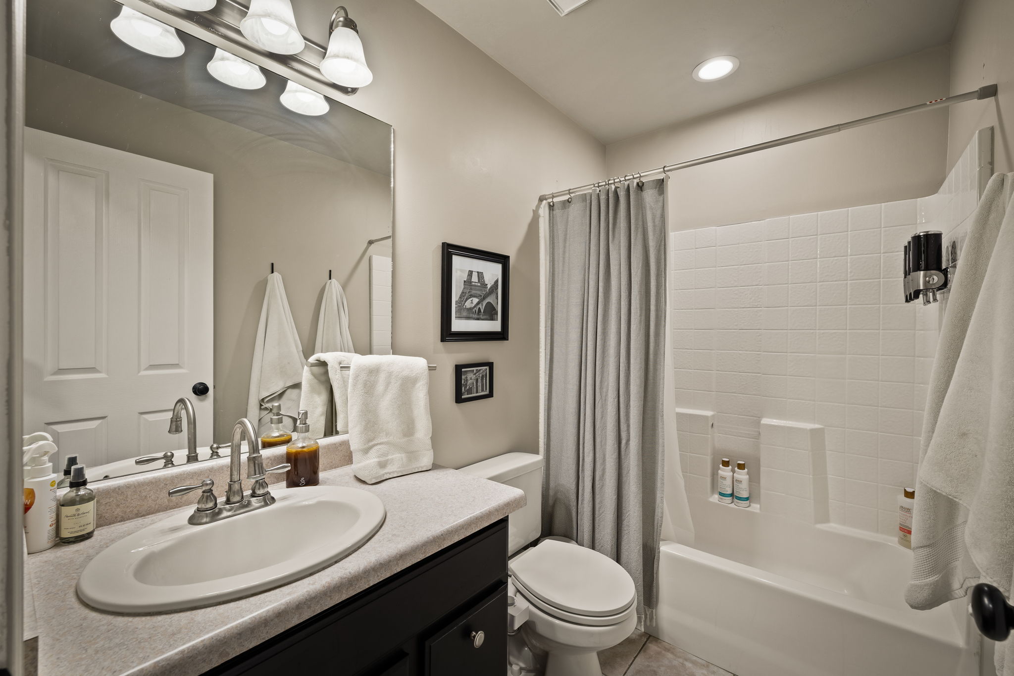 Bathroom featuring a single vanity with an oval sink, brushed nickel faucet, and dark wood-finish cabinetry