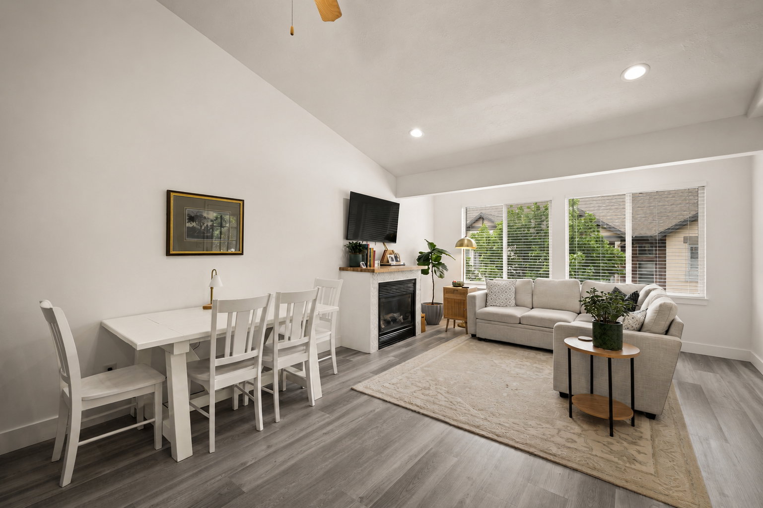 Open-concept living area with vaulted ceilings, gray wood-finish flooring, and recessed lighting