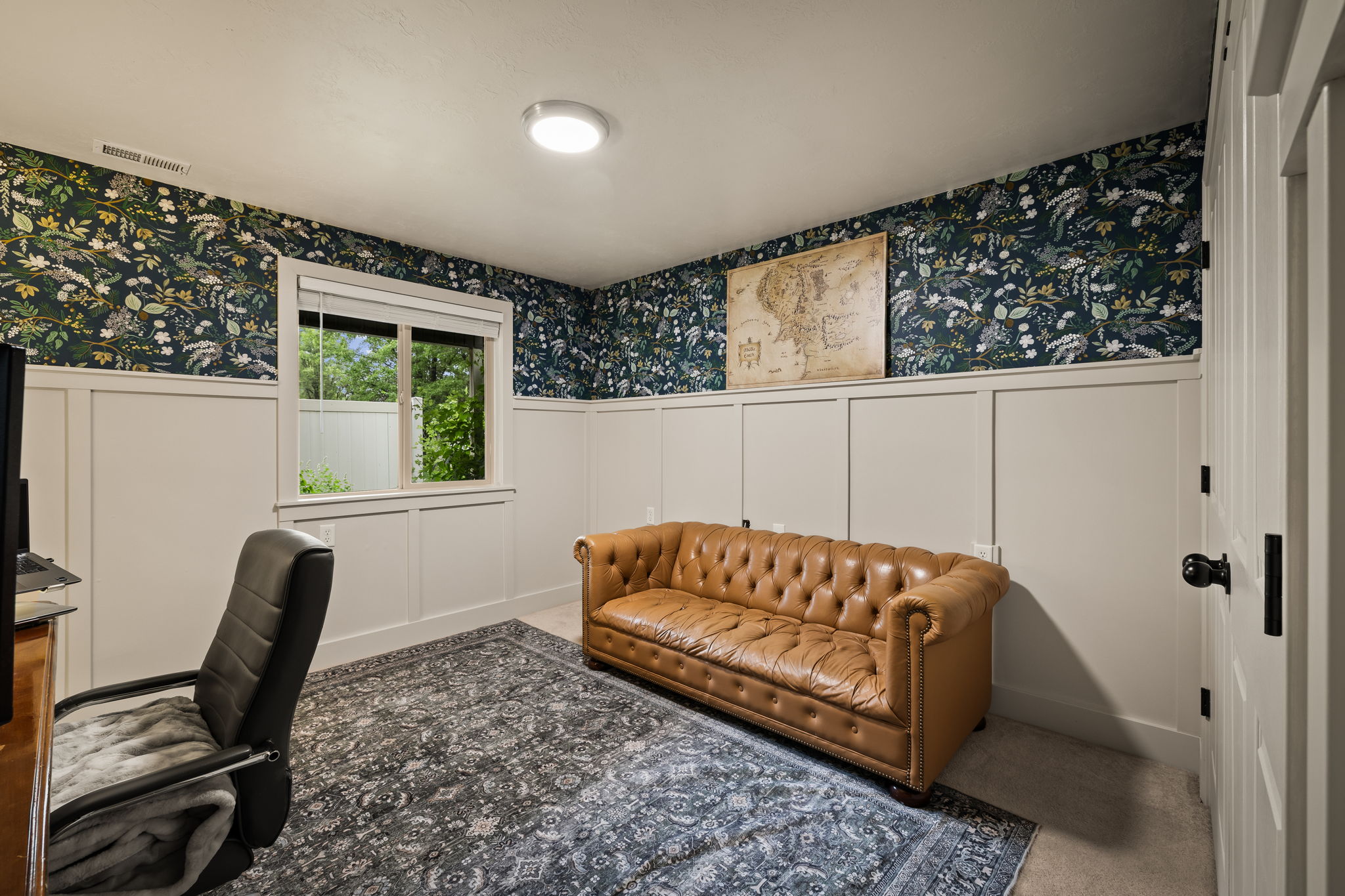 Room featuring wainscoting with a decorative top trim, patterned wallpaper, and a recessed window