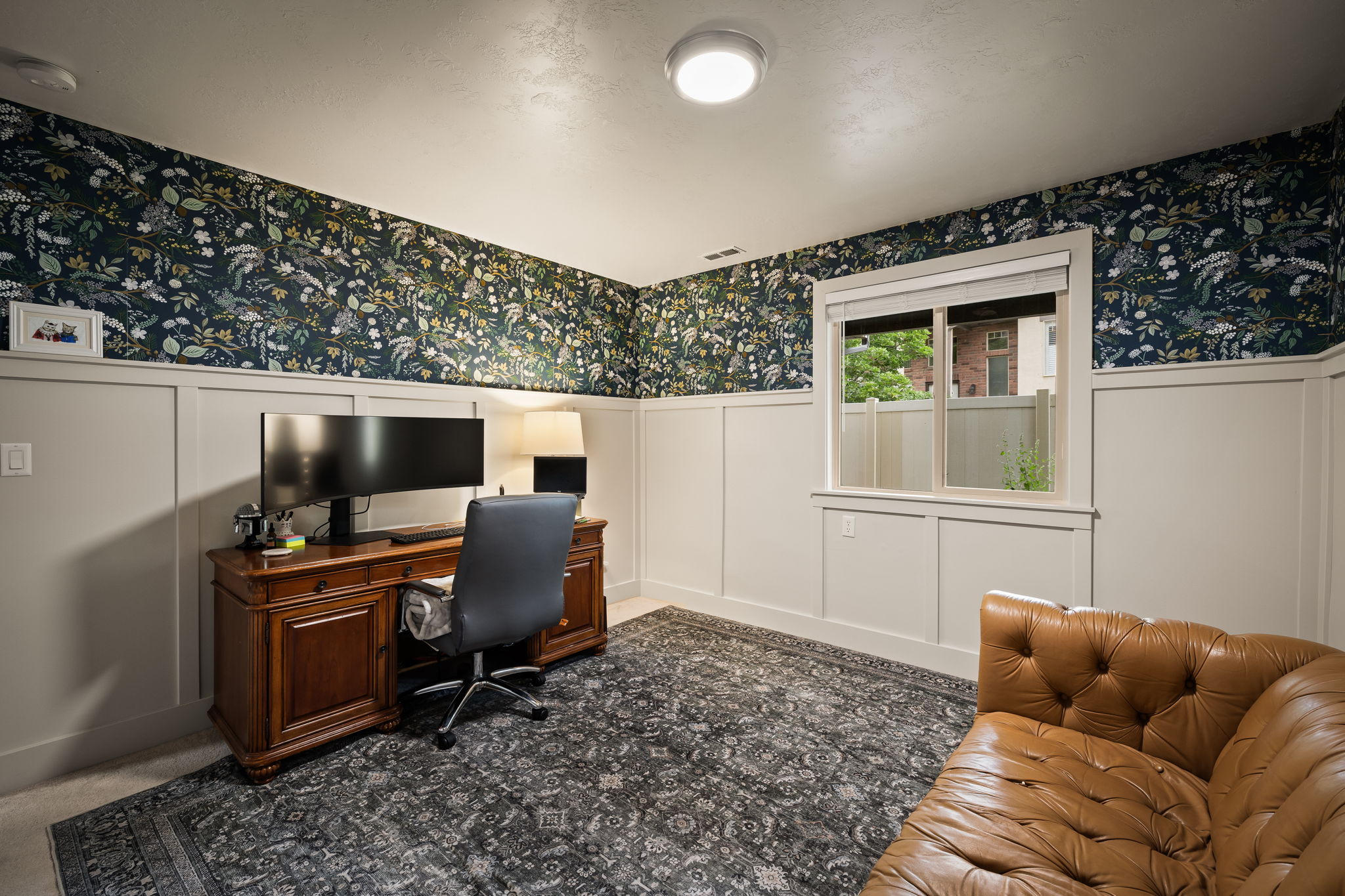 Room featuring wainscoting and botanical-patterned wallpaper