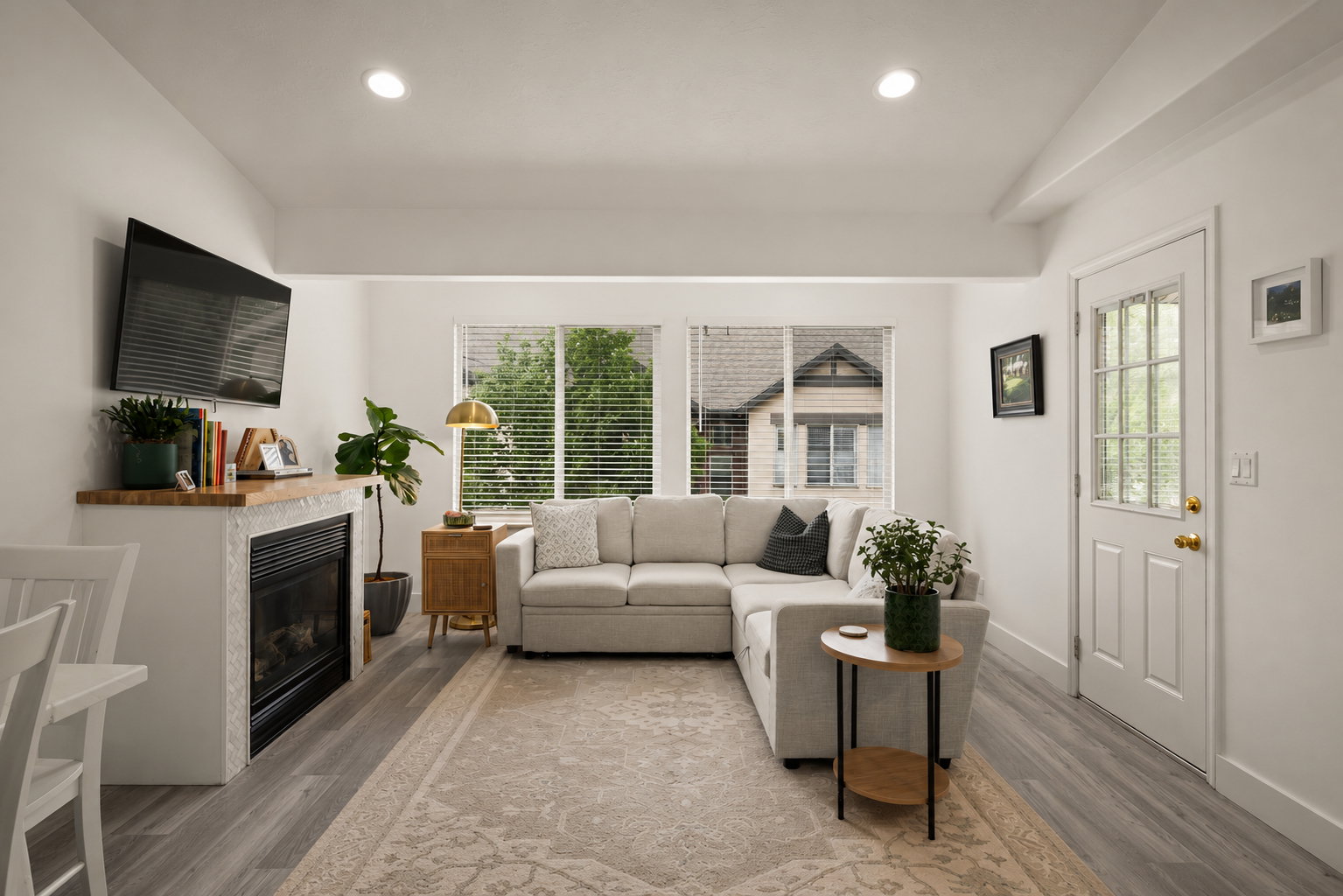 Bright living area featuring wood-finish flooring, recessed lighting, and a white paneled entry door with glass inserts