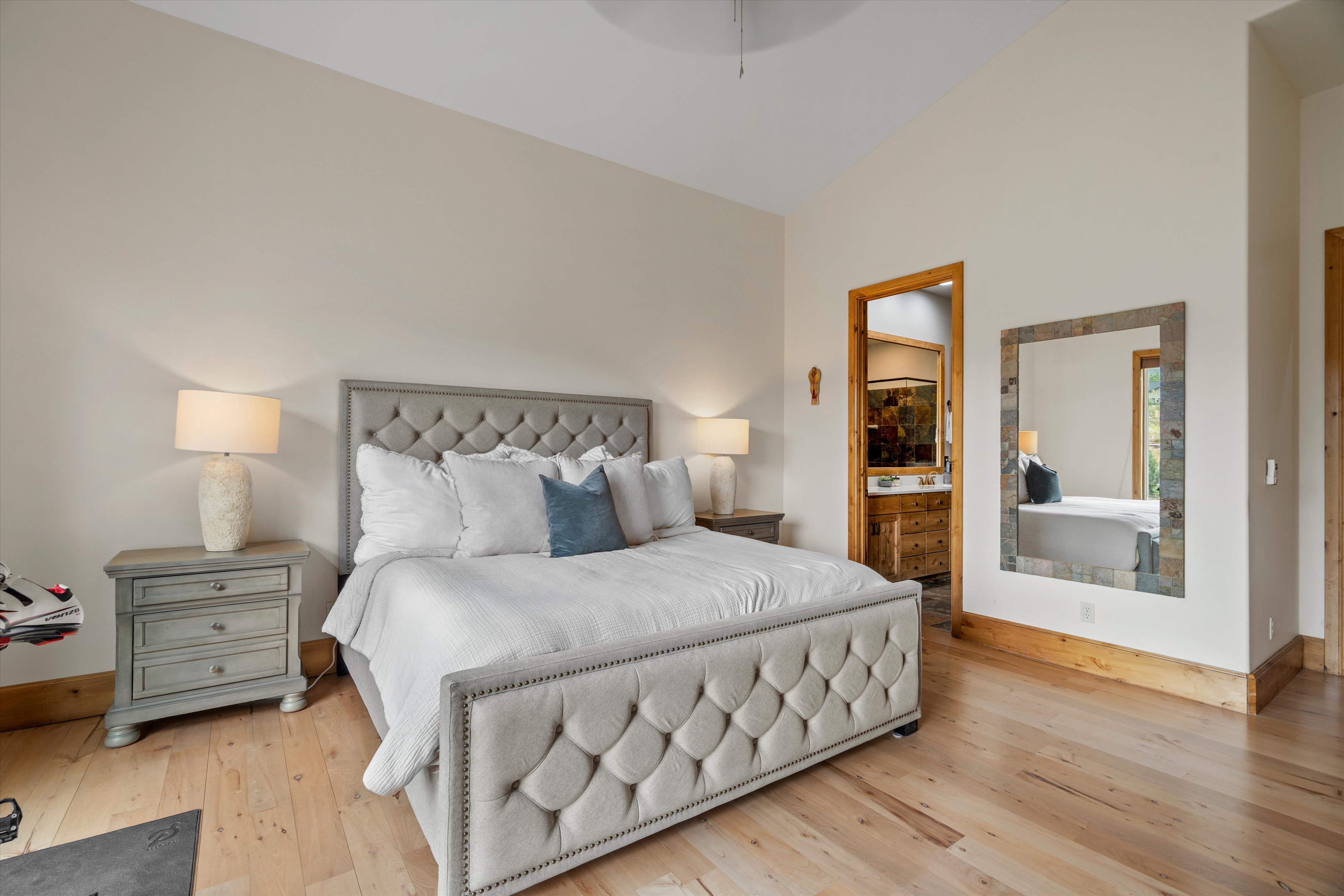 Vaulted ceiling bedroom featuring light wood-finish flooring and substantial wood trim