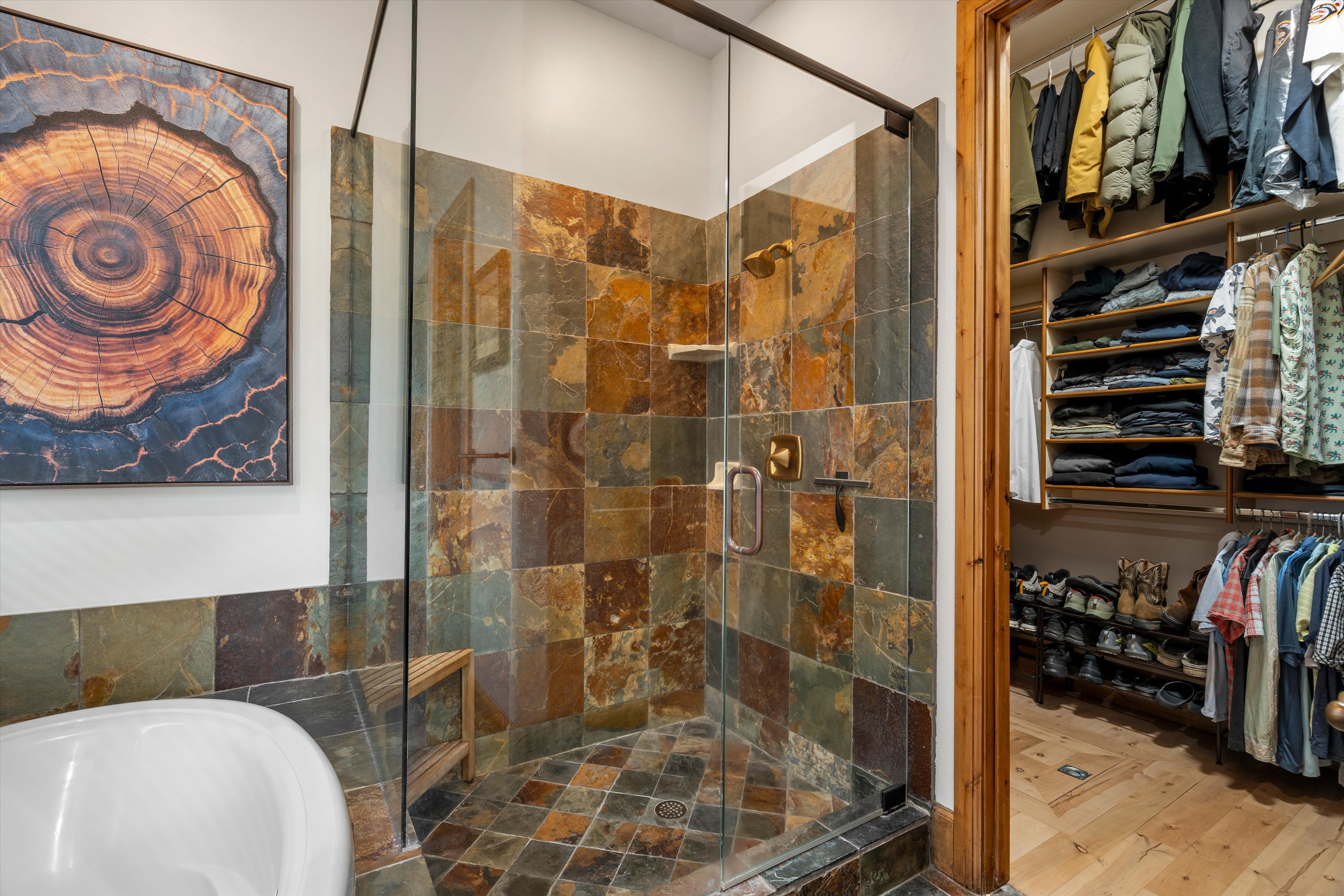 Walk-in shower featuring multi-toned slate tile, a glass enclosure, and a built-in wooden bench