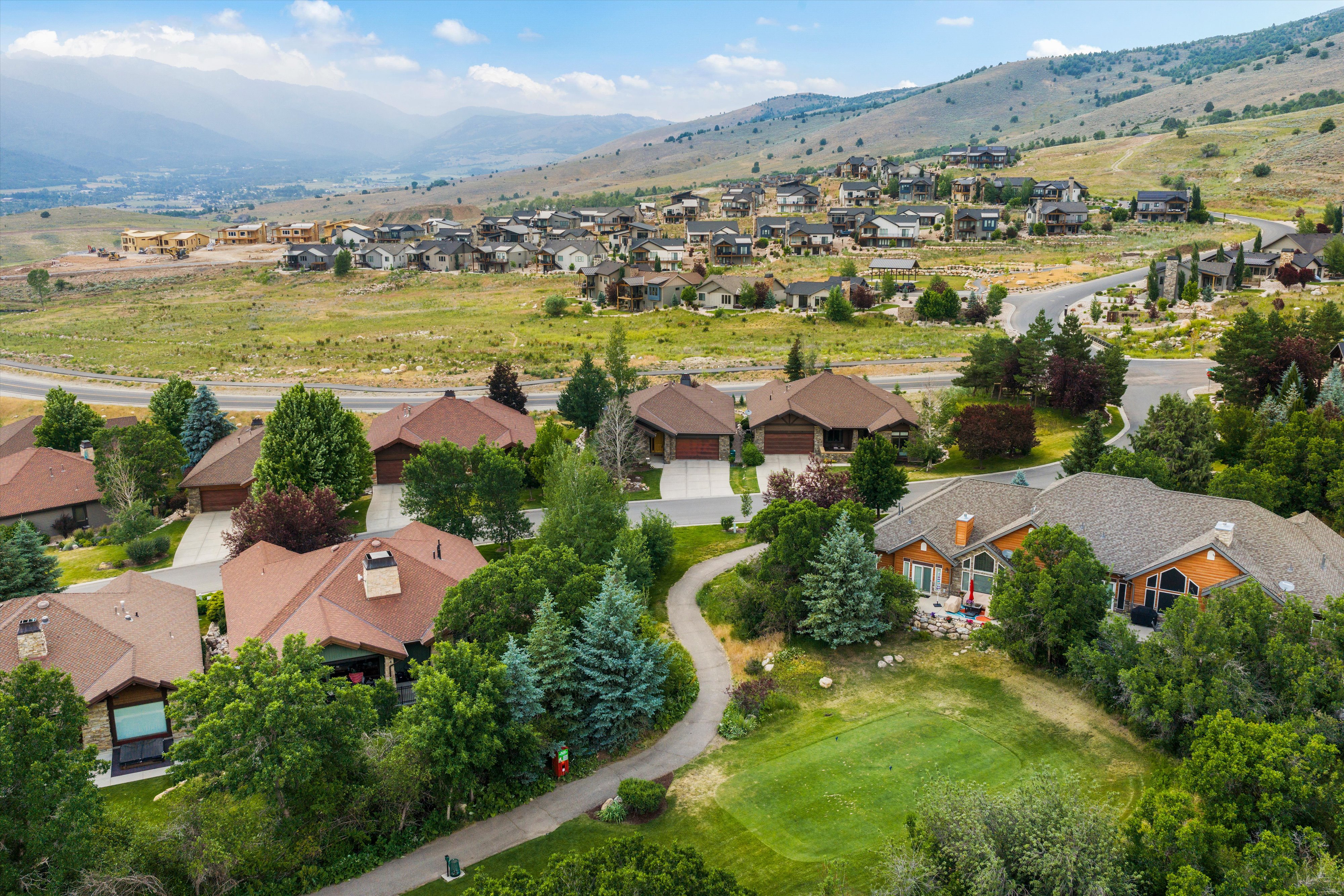 Residential properties featuring brown shingle roofs, attached garages, and mature landscaping