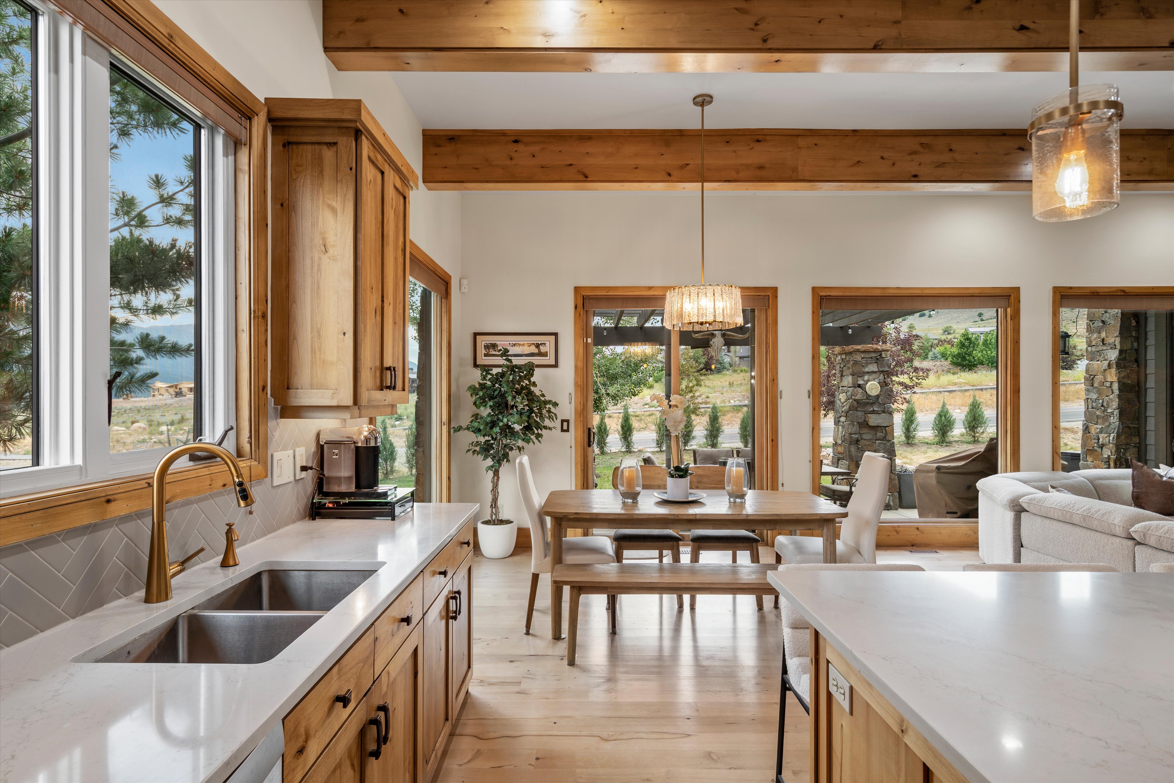 Gourmet kitchen featuring a double basin stainless steel sink, brass faucet, light wood-finish cabinetry, and white countertops