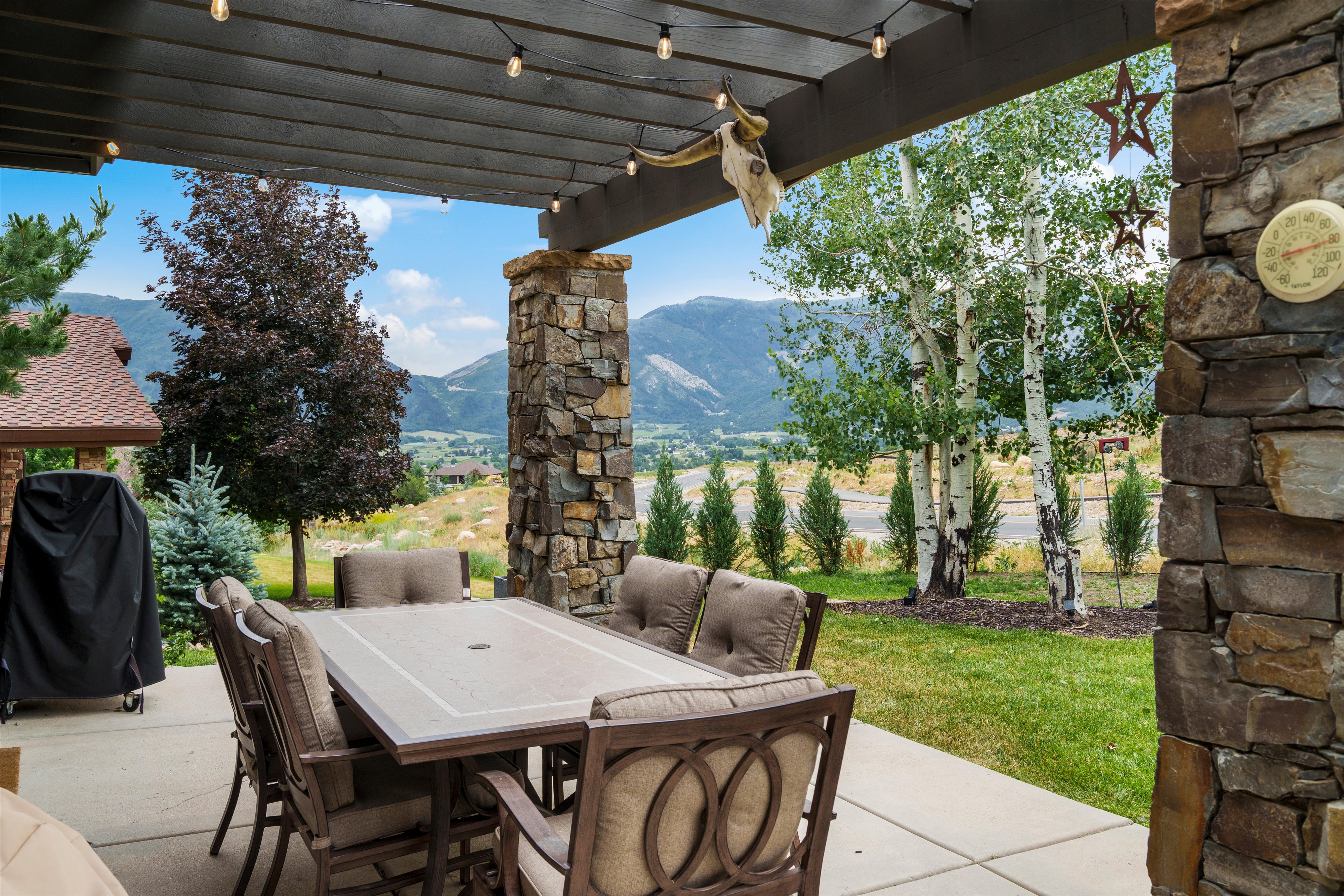 Covered outdoor patio featuring a concrete slab, string lighting, and stone support columns