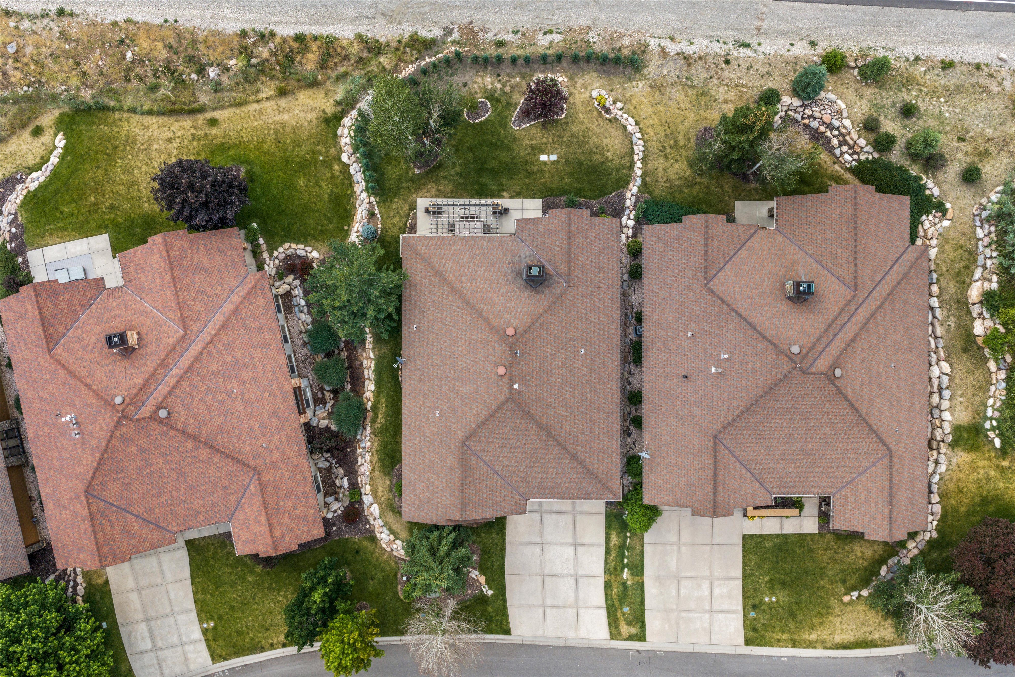Aerial overview showcasing three residential properties with brown shingle roofing