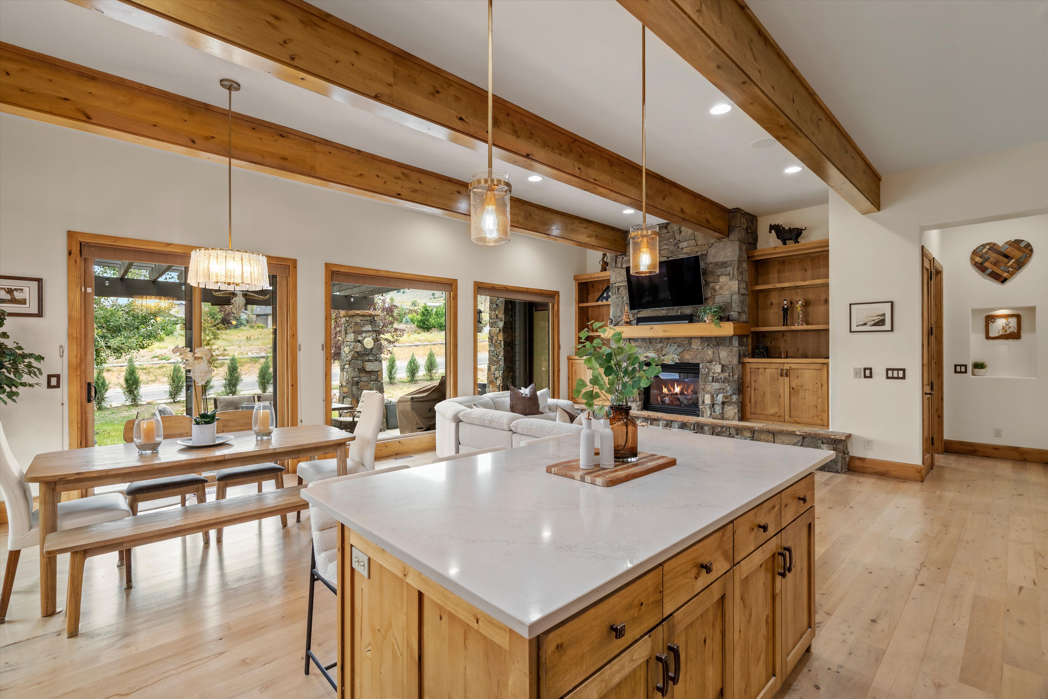 Spacious open-concept interior featuring light wood-finish flooring and exposed ceiling beams