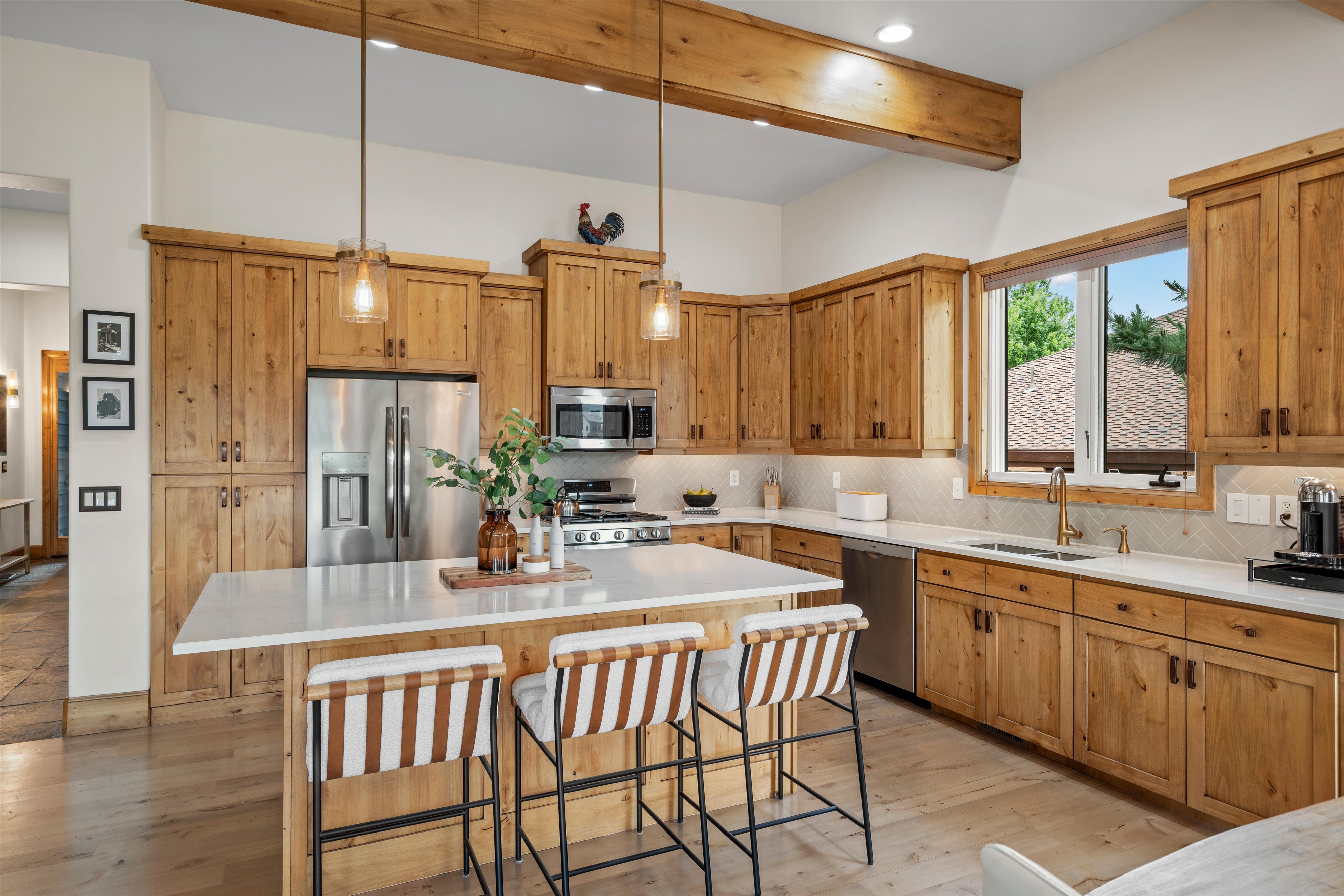 Kitchen featuring natural wood cabinetry, a large central island with seating, stainless steel appliances, a tile backsplash, and wood-finish flooring