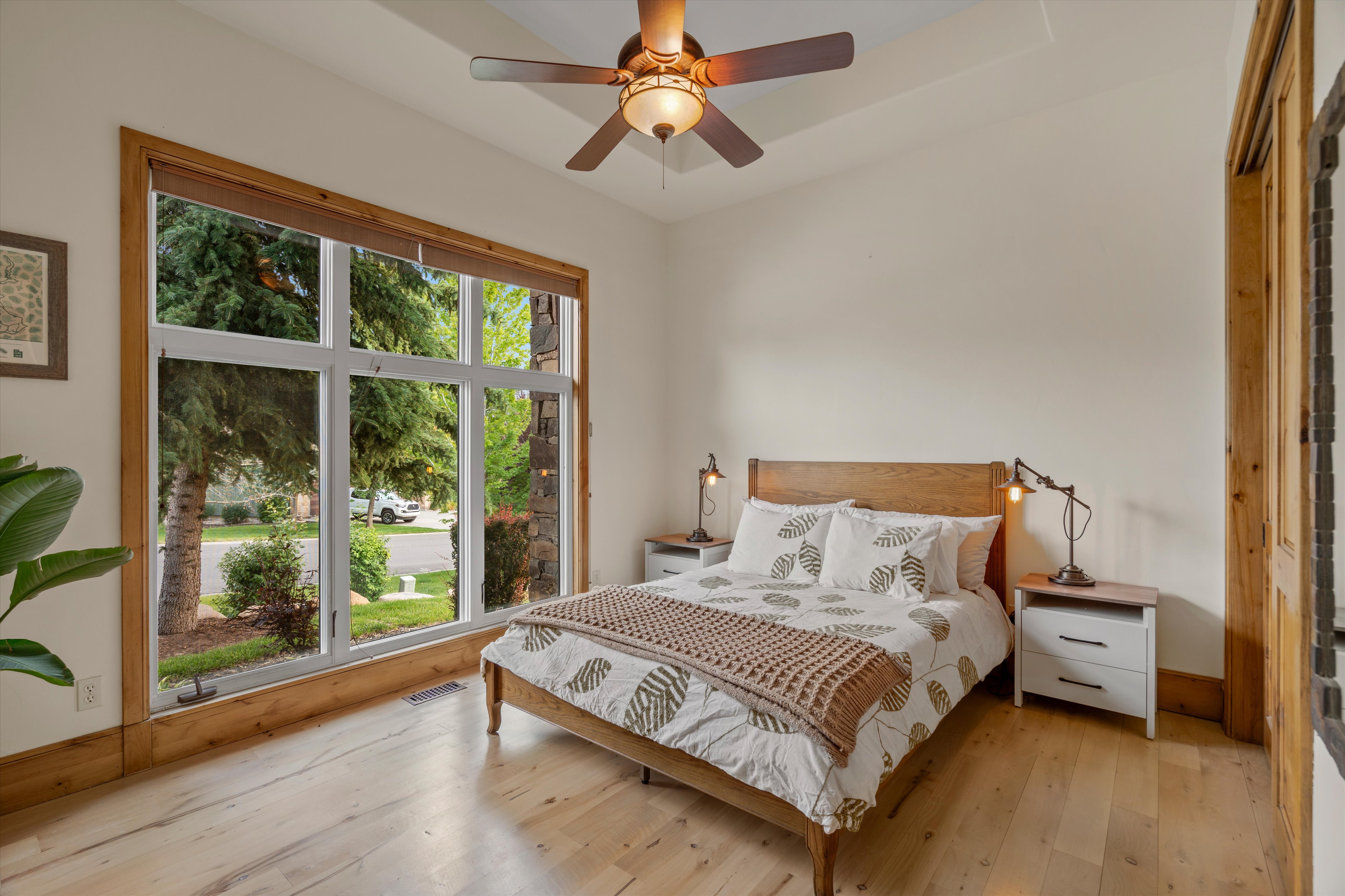 Spacious room featuring a large multi-pane window with wood trim, wood-finish flooring, a tray ceiling, and a ceiling fan with integrated lighting