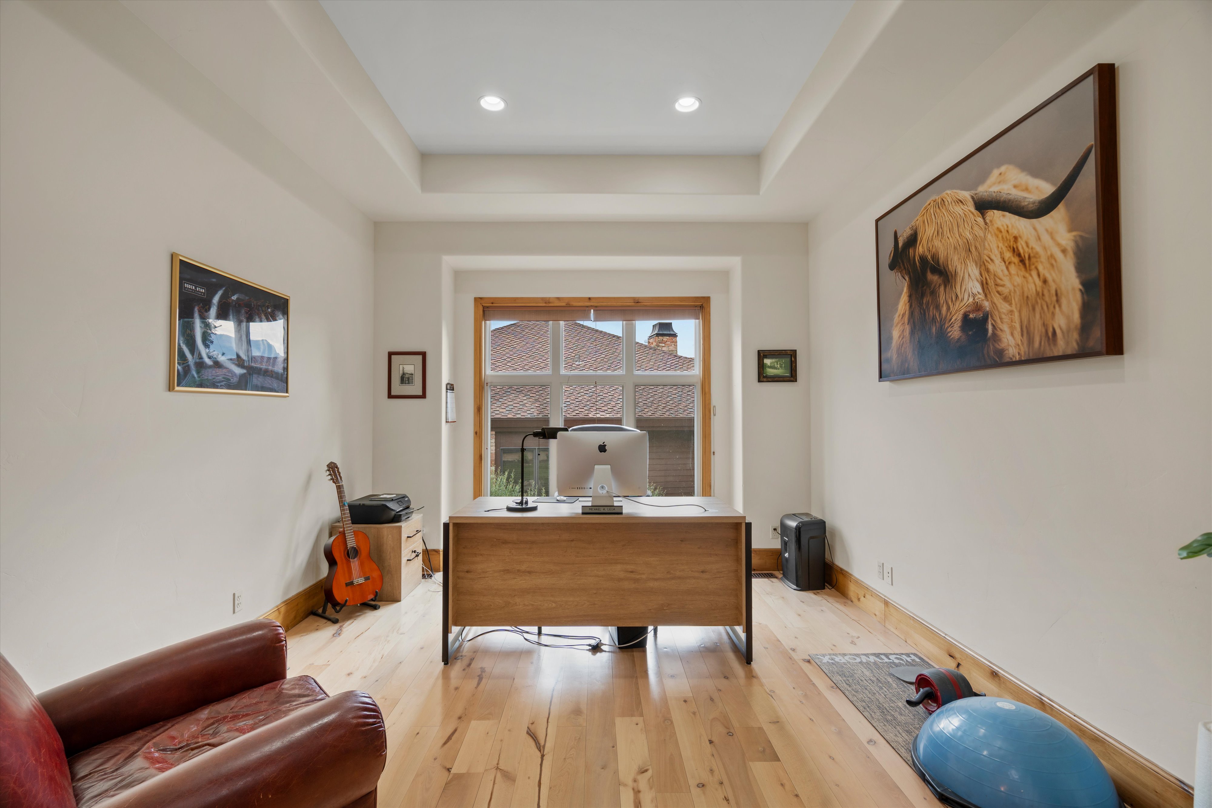 Spacious room featuring wood-finish flooring, light-toned walls, and a tray ceiling with recessed lighting