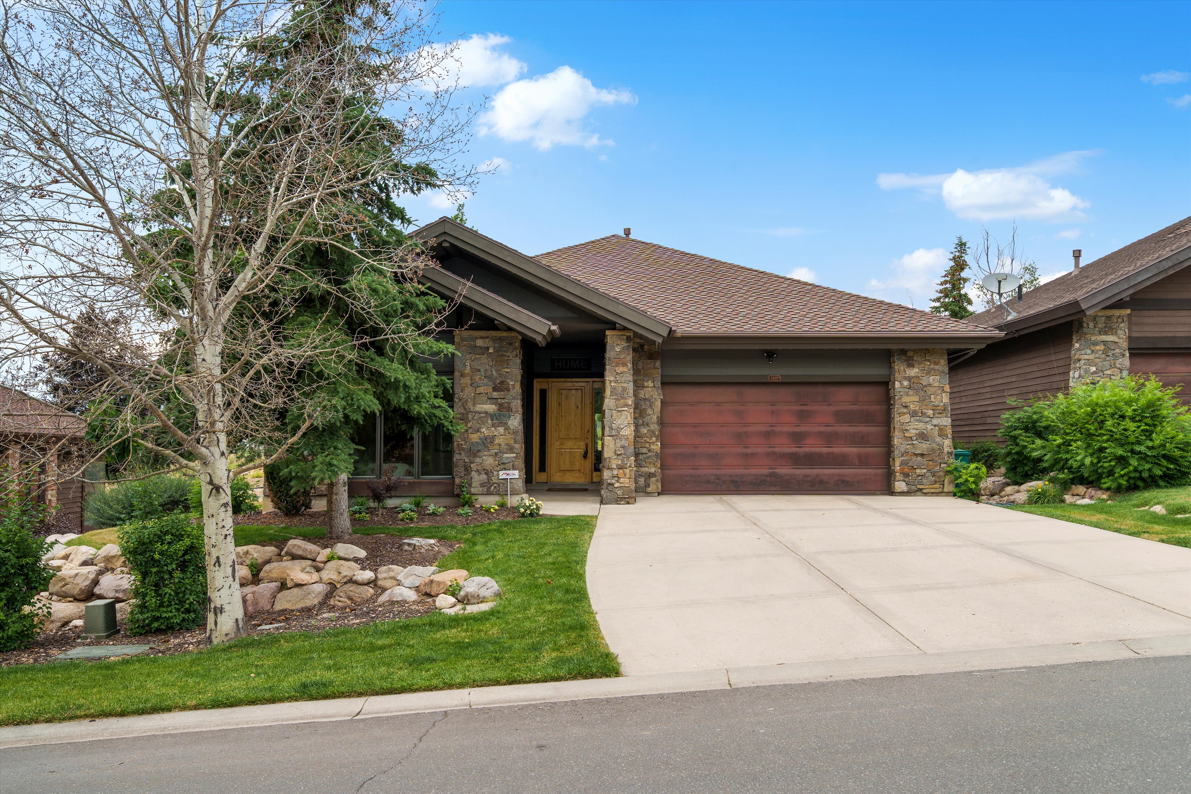 Contemporary single-story residence with a multi-gabled roofline and stone-clad columns