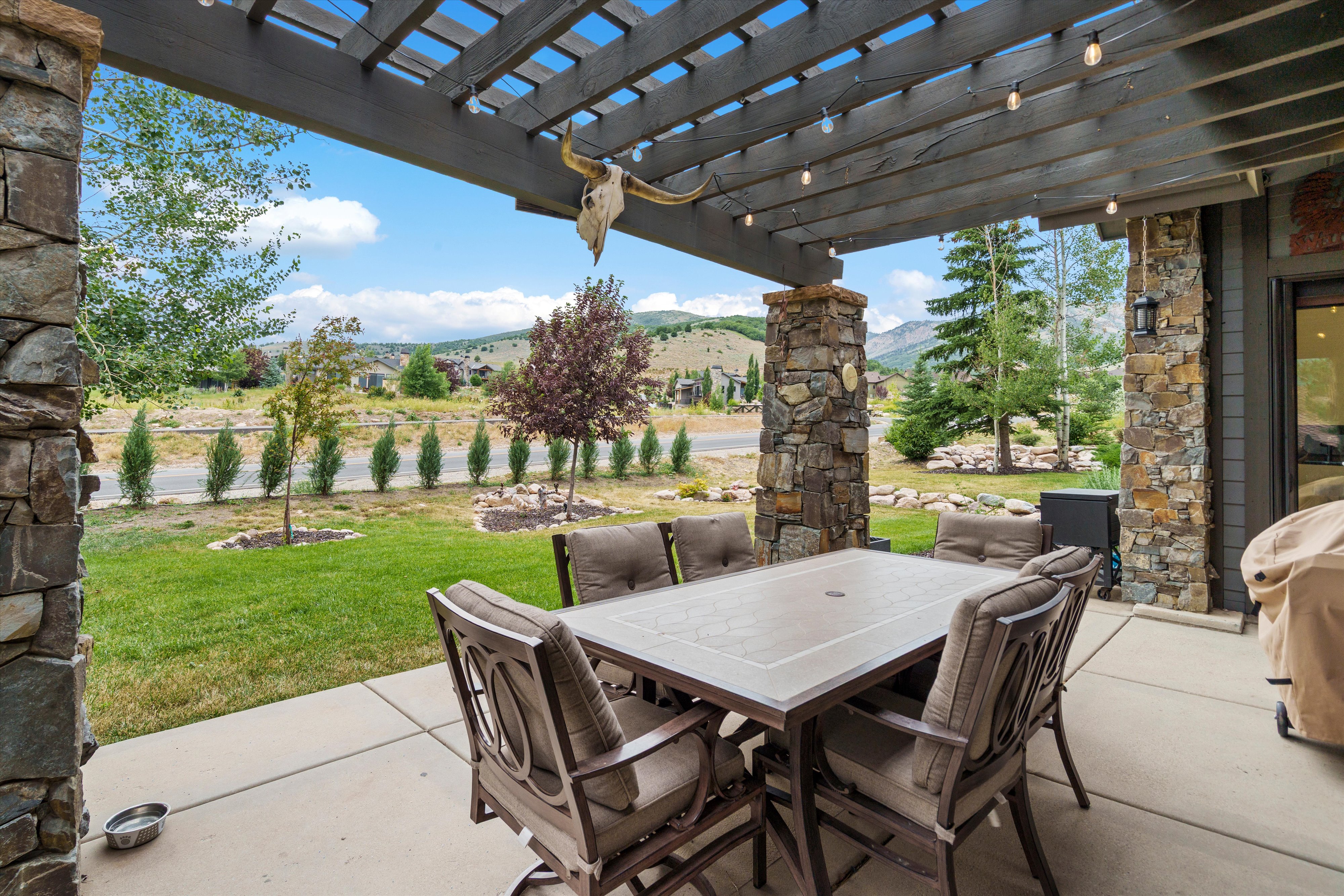 Expansive covered patio featuring a wood pergola and stone columns