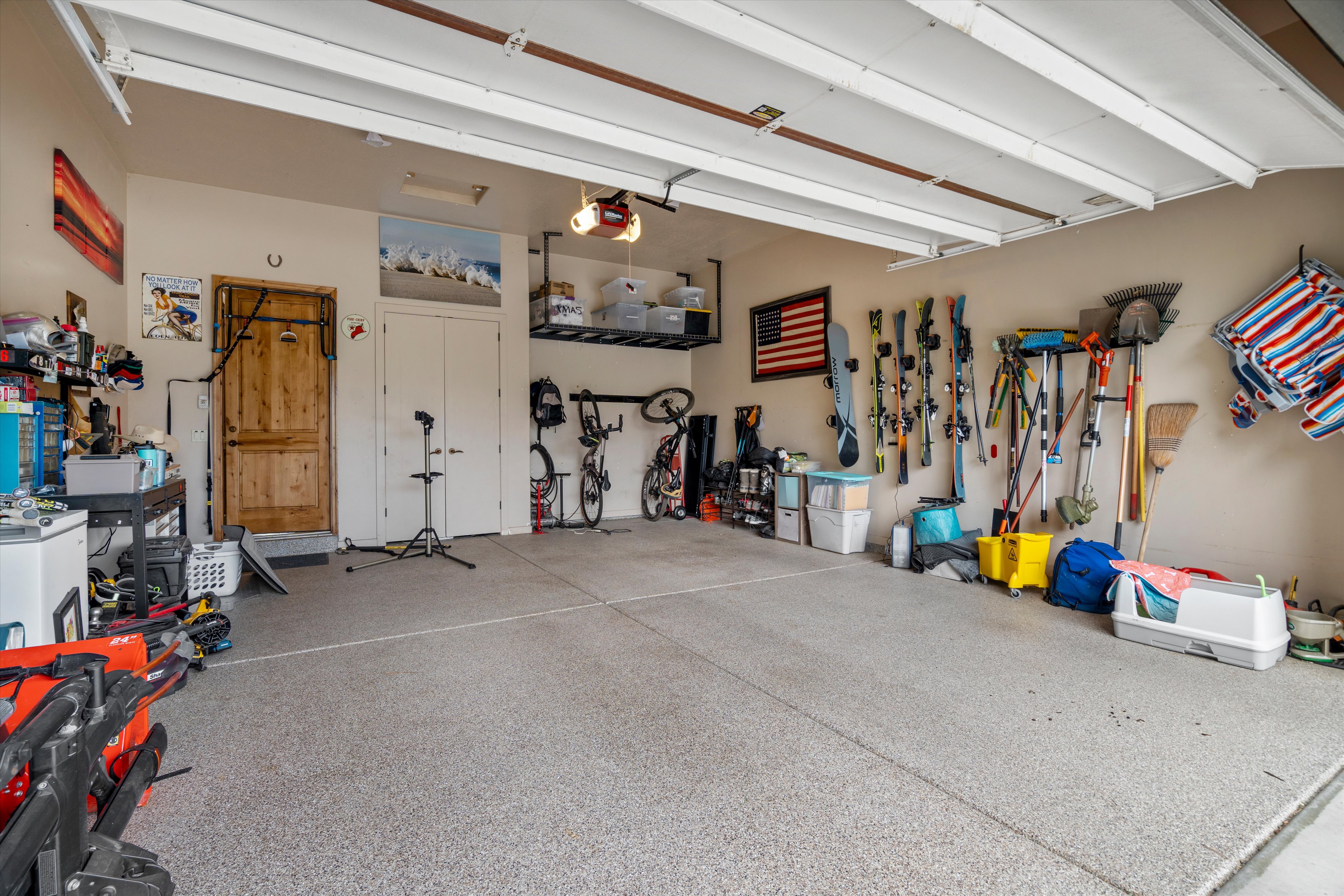 Spacious garage with an epoxy-coated floor, overhead storage racking, and a wooden entry door