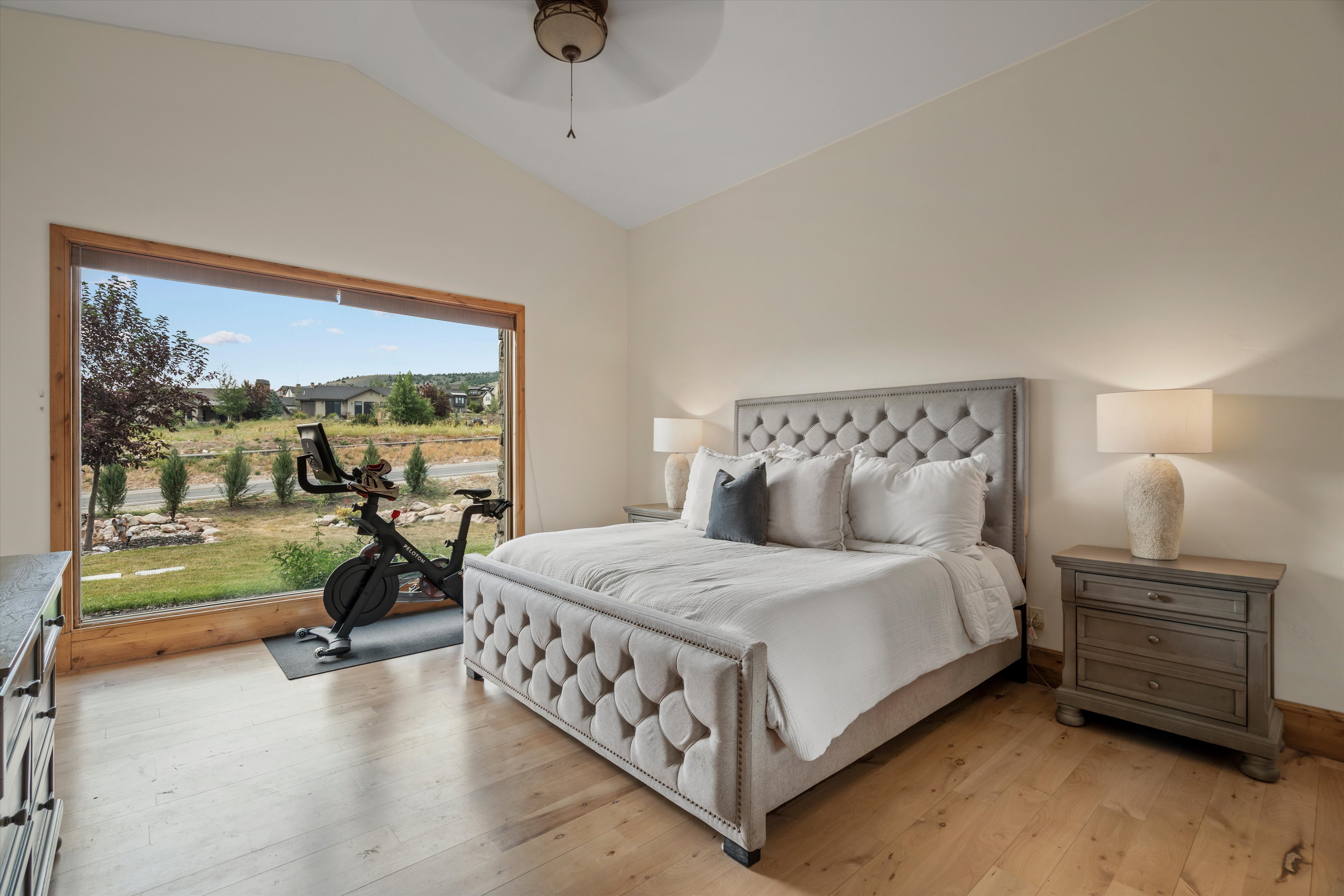 Vast picture window, vaulted ceiling, wood-finish flooring, recessed lighting, and a ceiling fan
