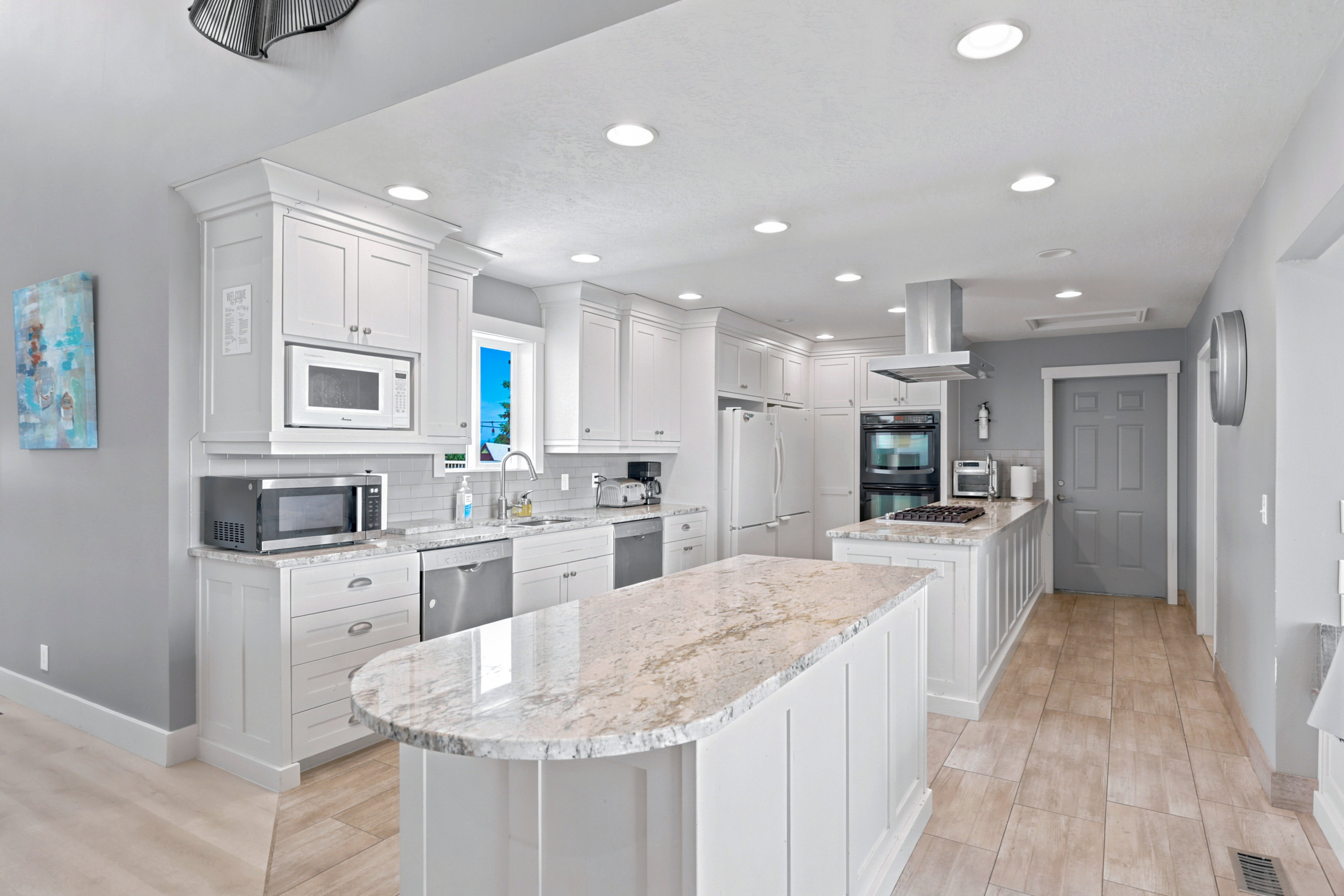 Kitchen featuring two islands with stone countertops, white cabinetry, stainless steel appliances, and recessed lighting