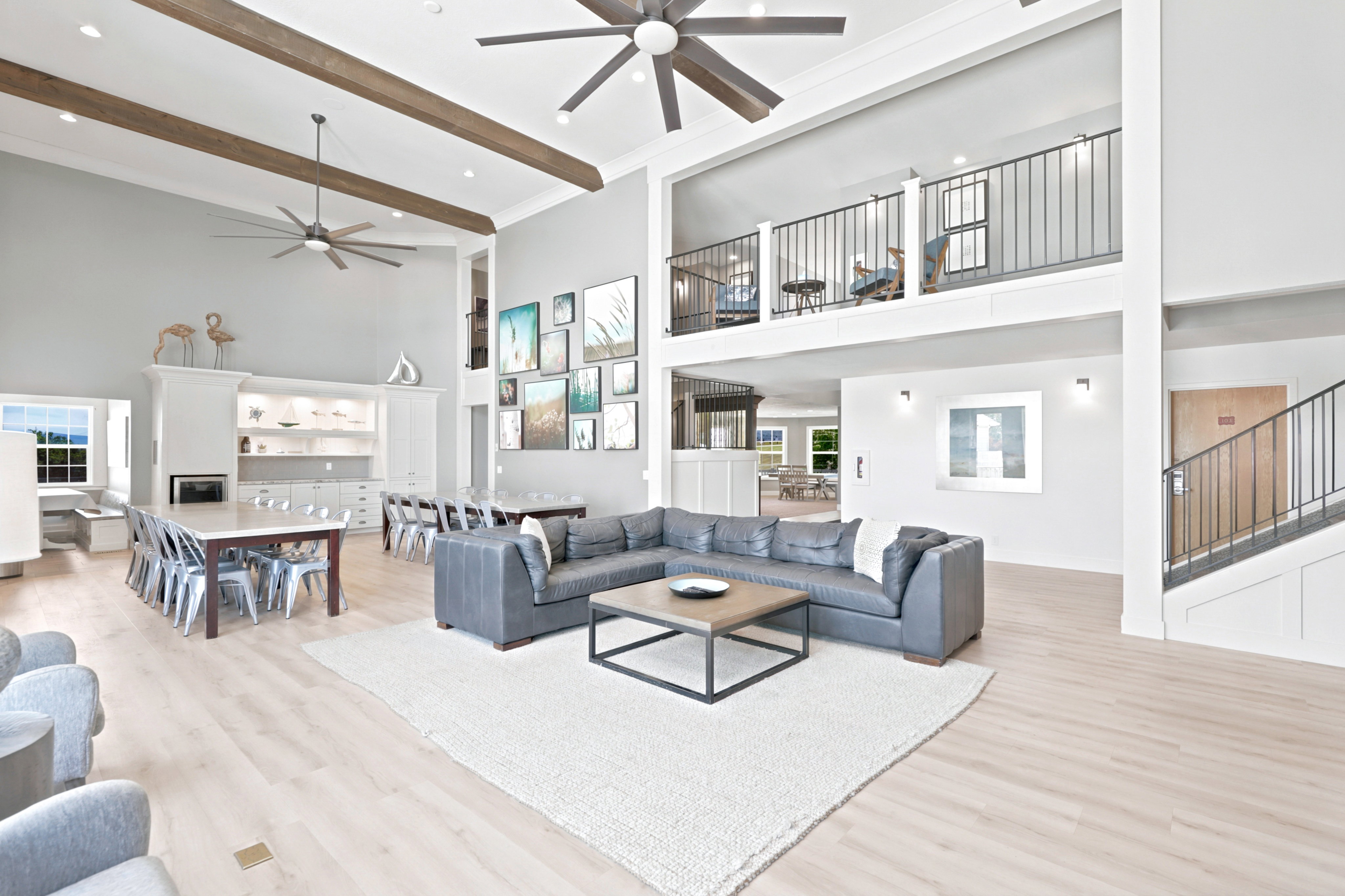 Expansive open-concept space featuring soaring ceilings with exposed wood beams and ceiling fans