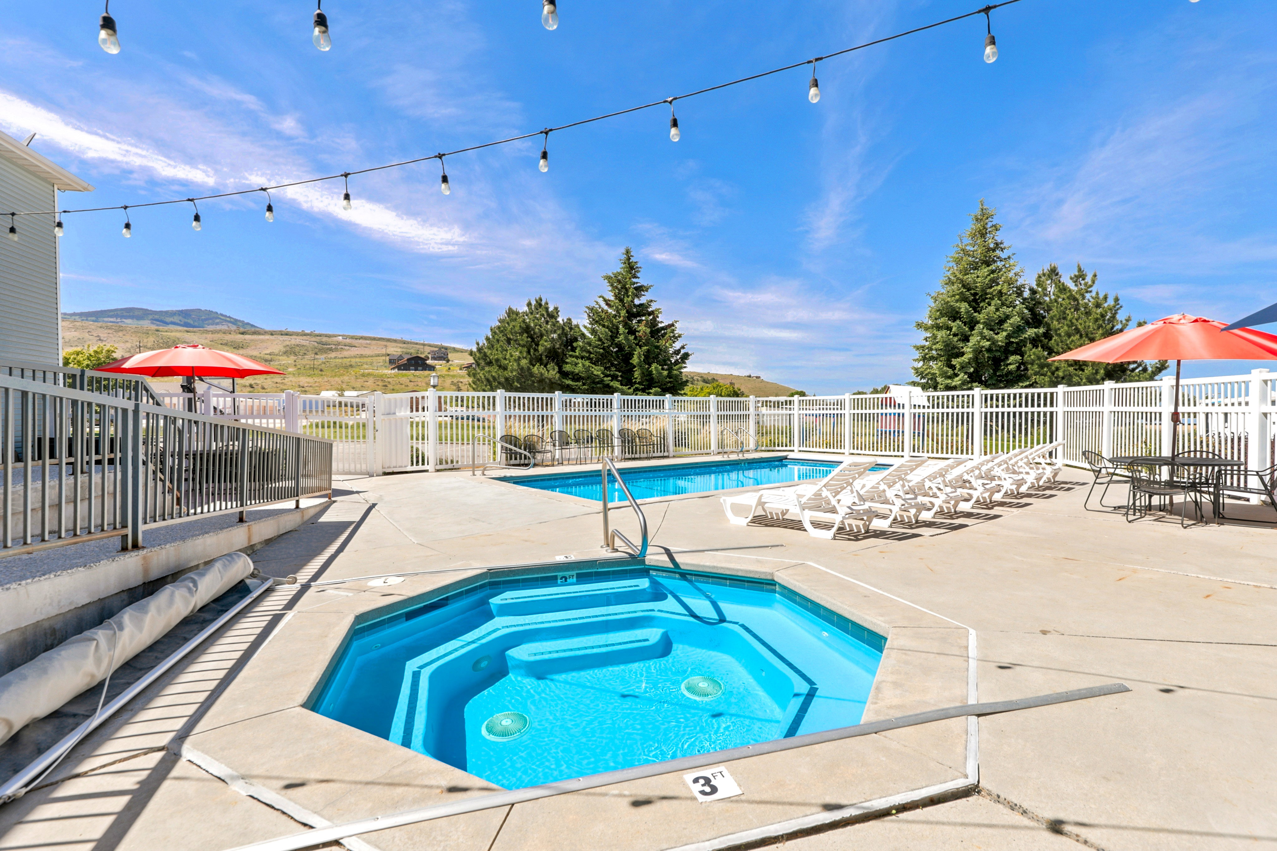 Outdoor pool area featuring a hot tub and an adjacent swimming pool, surrounded by a concrete deck