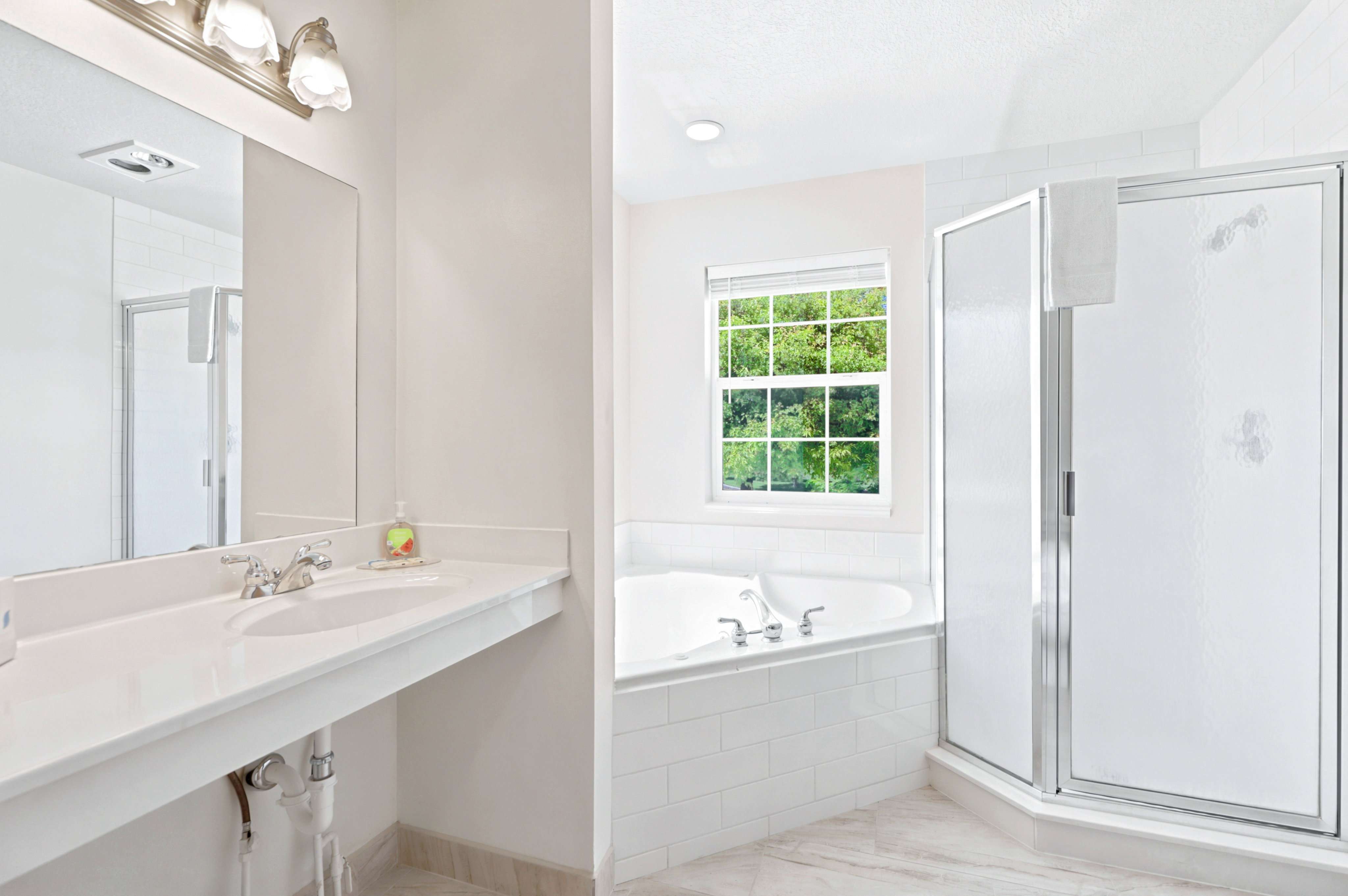 Bathroom featuring a dual vanity with white countertop, chrome fixtures, and an overhead light bar