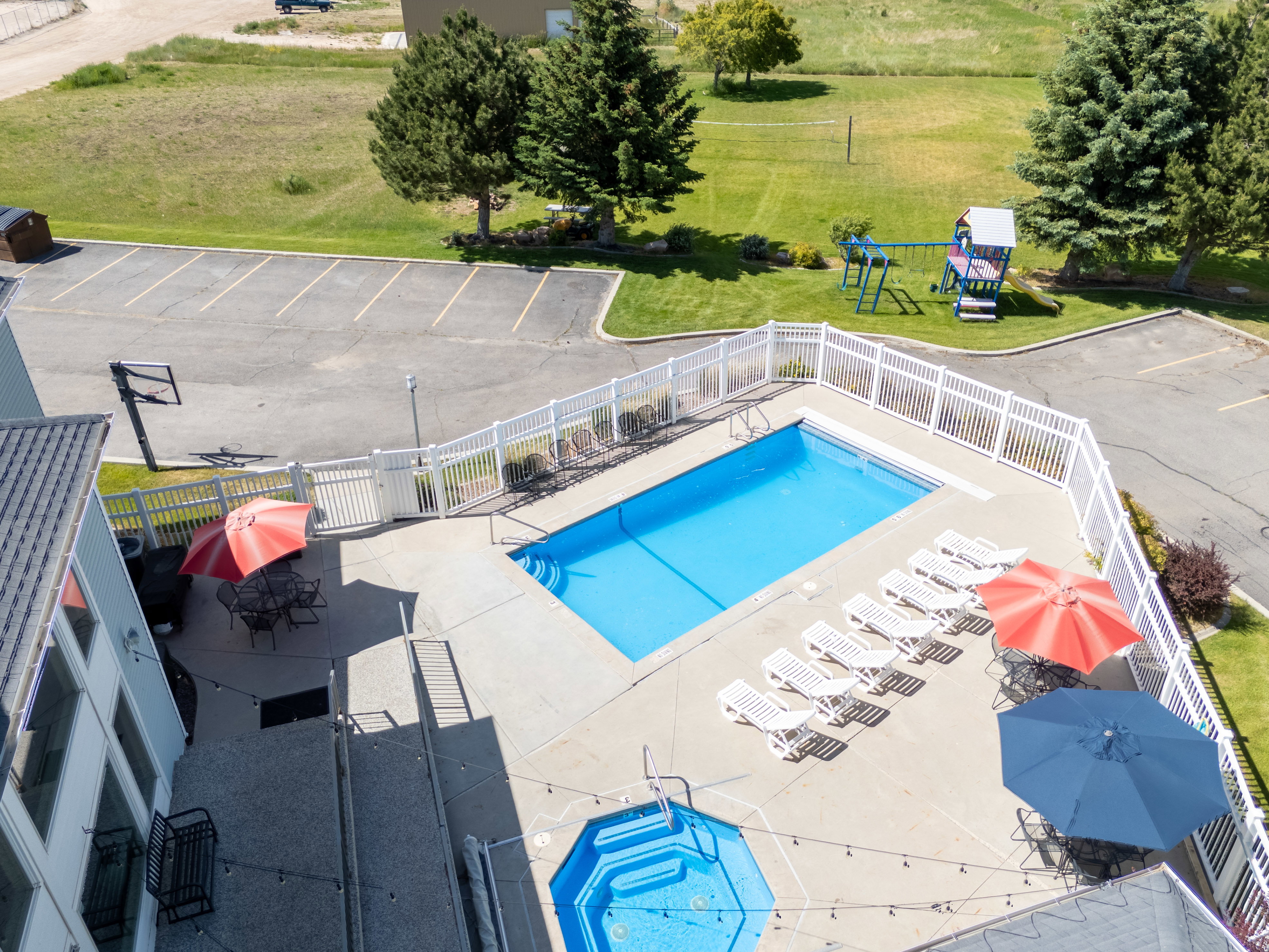 Fenced outdoor pool area featuring a rectangular swimming pool, integrated spa, and expansive concrete decking