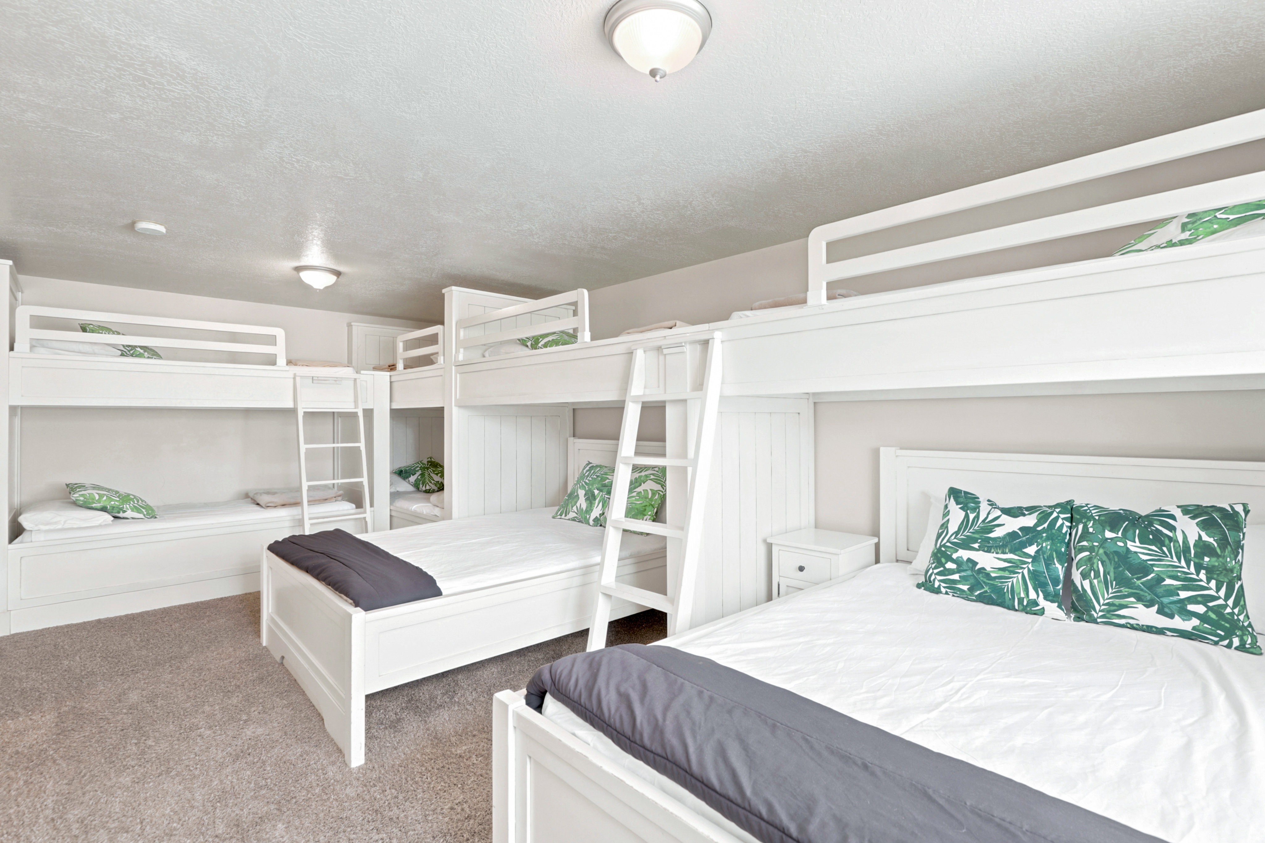 Spacious bedroom featuring multiple built-in white bunk beds, light gray wall paint, and recessed lighting