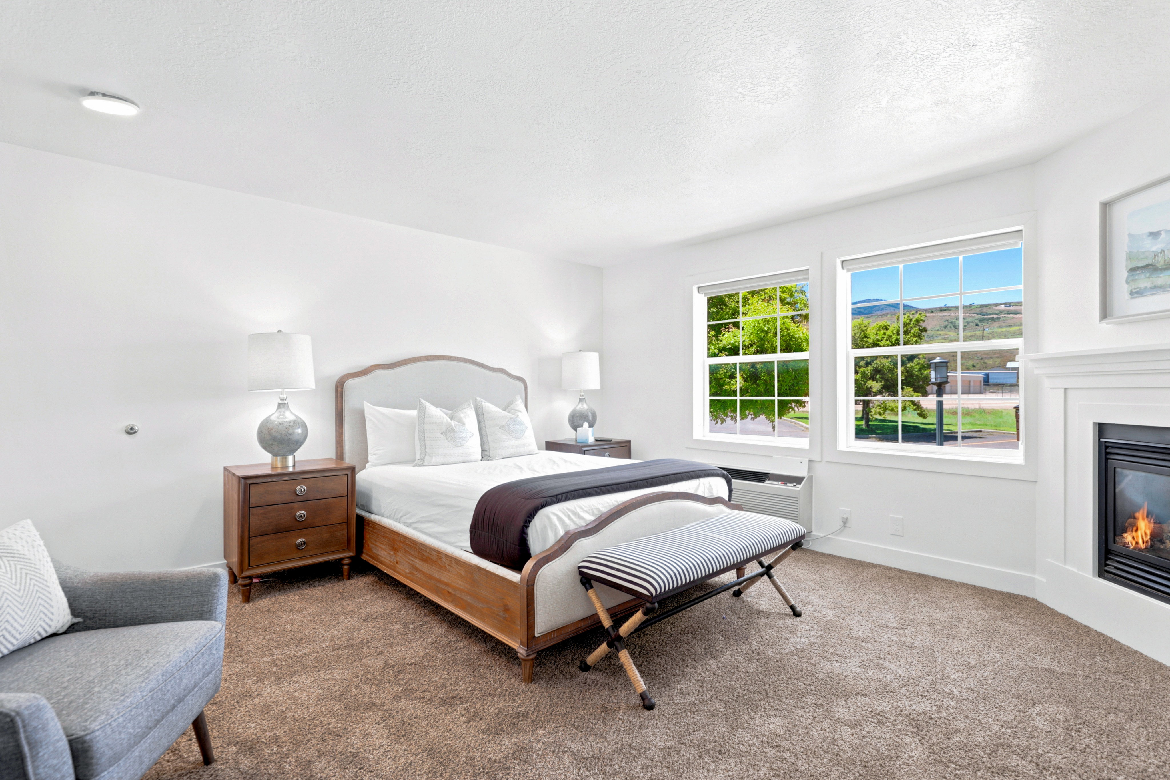 Carpeted room featuring a white fireplace, two large windows, and recessed lighting